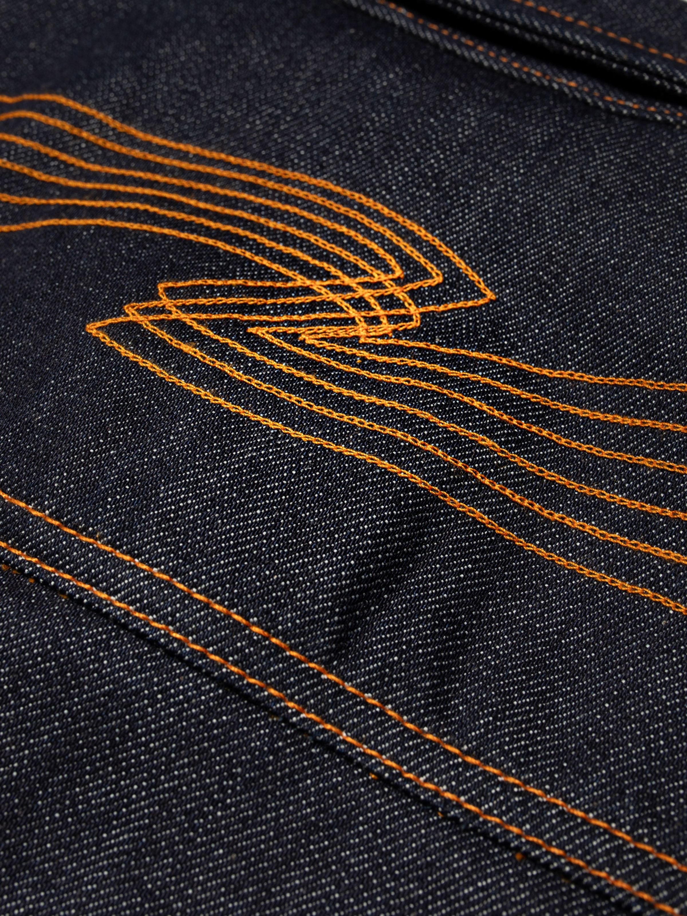 Nudie Jeans Conny Denim Jacket Dry One, a close-up of the orange back yoke embroidery on rigid organic cotton denim.