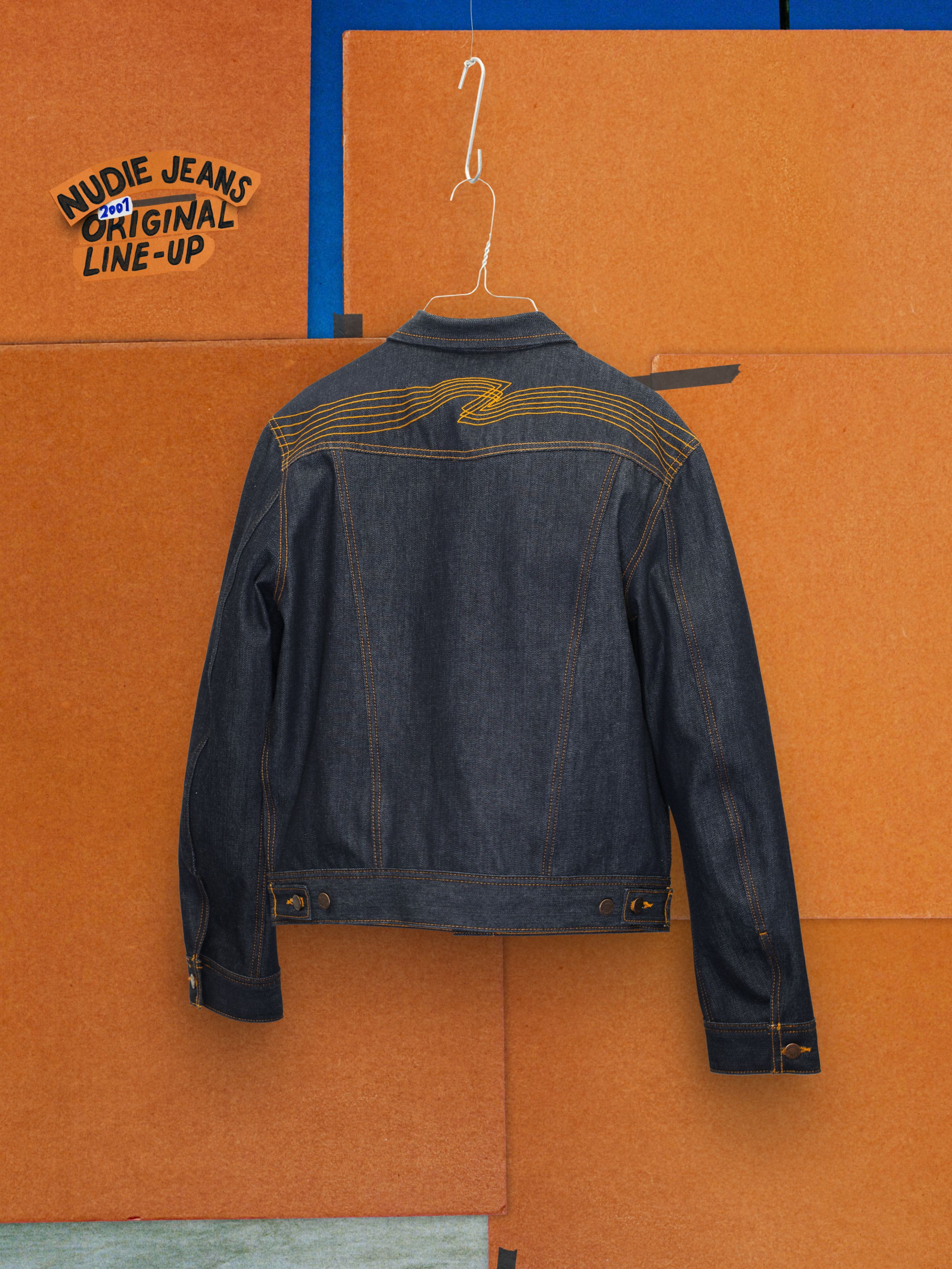 Nudie Jeans Conny Denim Jacket Dry One, back view featuring the signature orange yoke embroidery on rigid indigo denim.