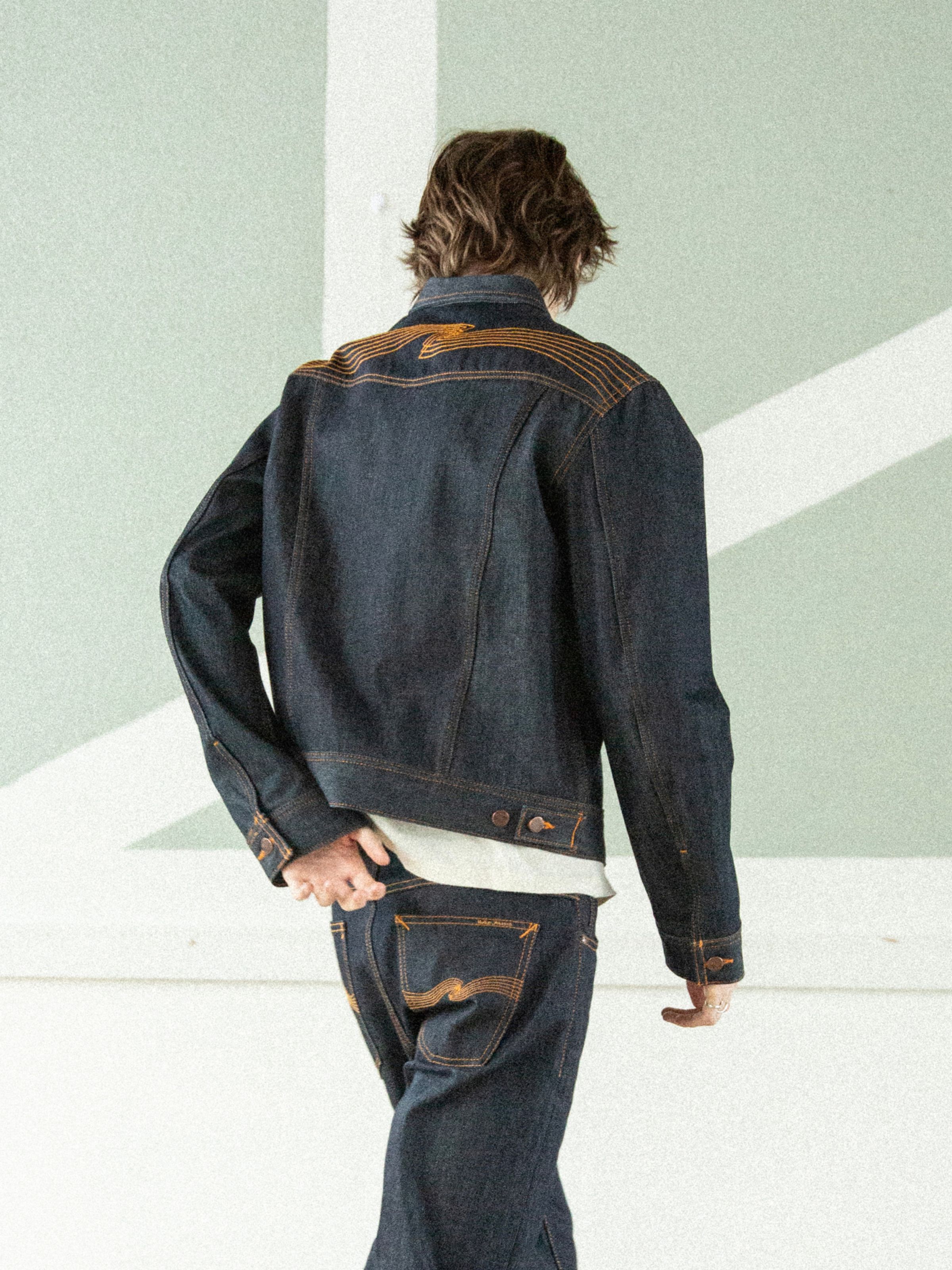 Nudie Jeans Conny Denim Jacket Dry One, Jeansjacke aus festem Indigo-Denim mit oranger Passe-Stickerei, Rückansicht am Model.