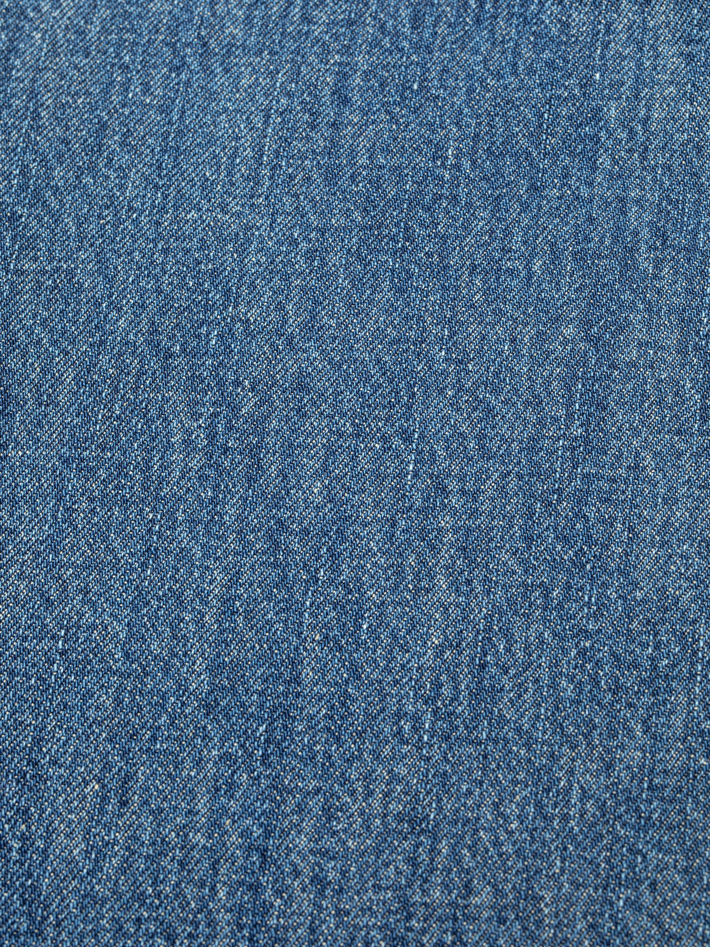 Nudie Jeans Clean Eileen Rust River, close-up of the mid-blue rigid denim fabric showing the texture.