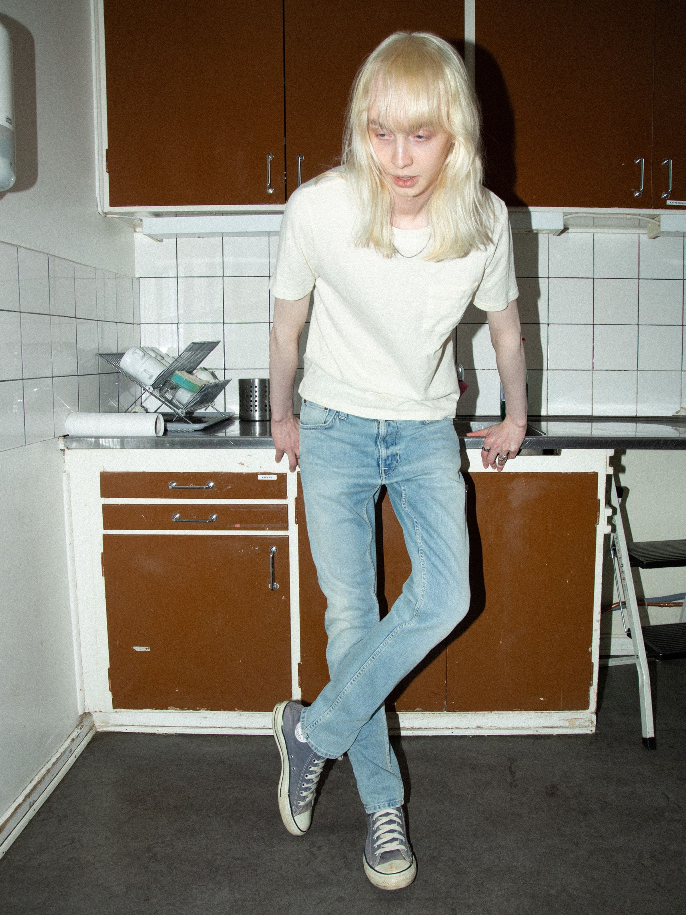 Nudie Jeans Lean Dean Shallow Sea, schmale Tapered-Herrenjeans, von vorne an einem Model in einer Küche gezeigt.