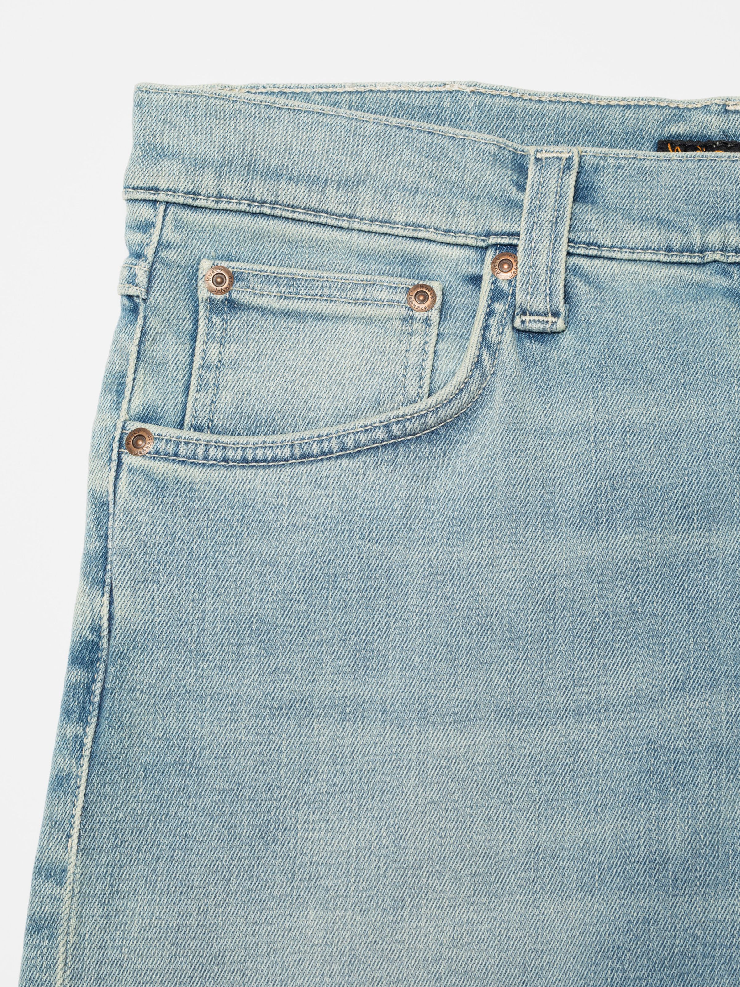 Nudie Jeans Lean Dean Shallow Sea, close-up of the front pocket area with copper trims and ecru stitching.