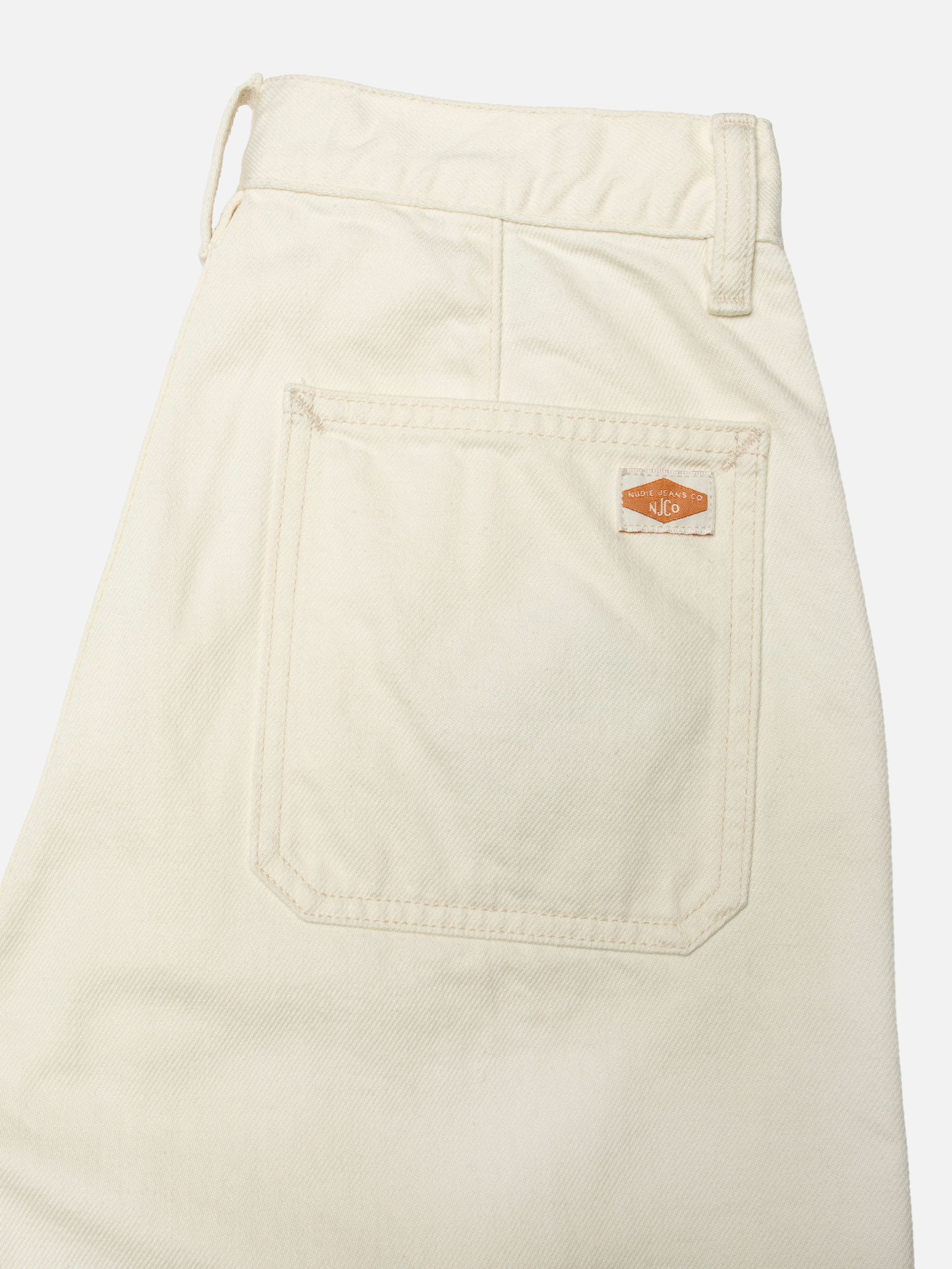 Nudie Jeans Asta Workwear Pants Ivory, close-up of the back pocket showing the logo label.