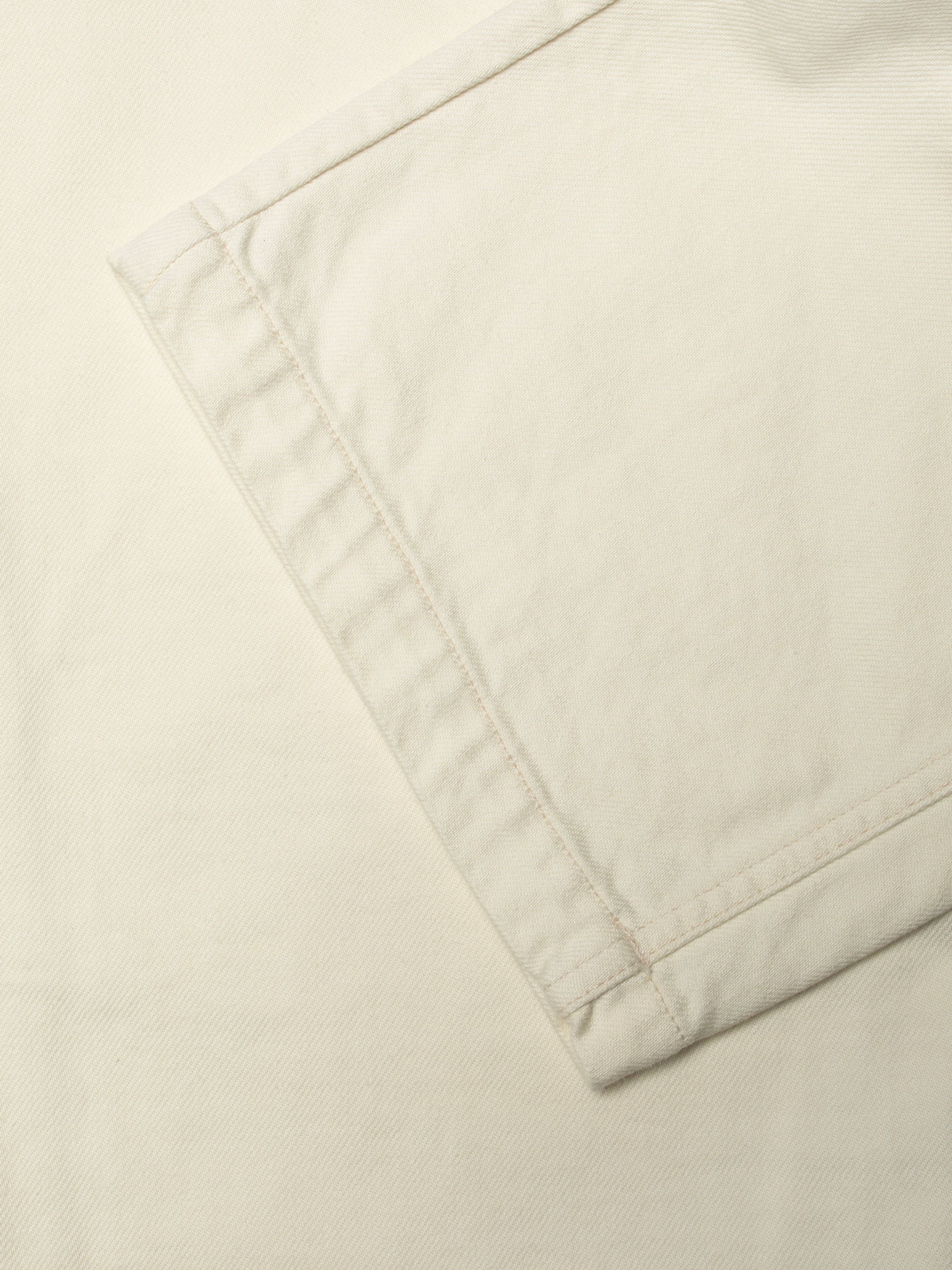 Nudie Jeans Asta Workwear Pants Ivory, close-up of the wide leg opening showing the ecru stitching.