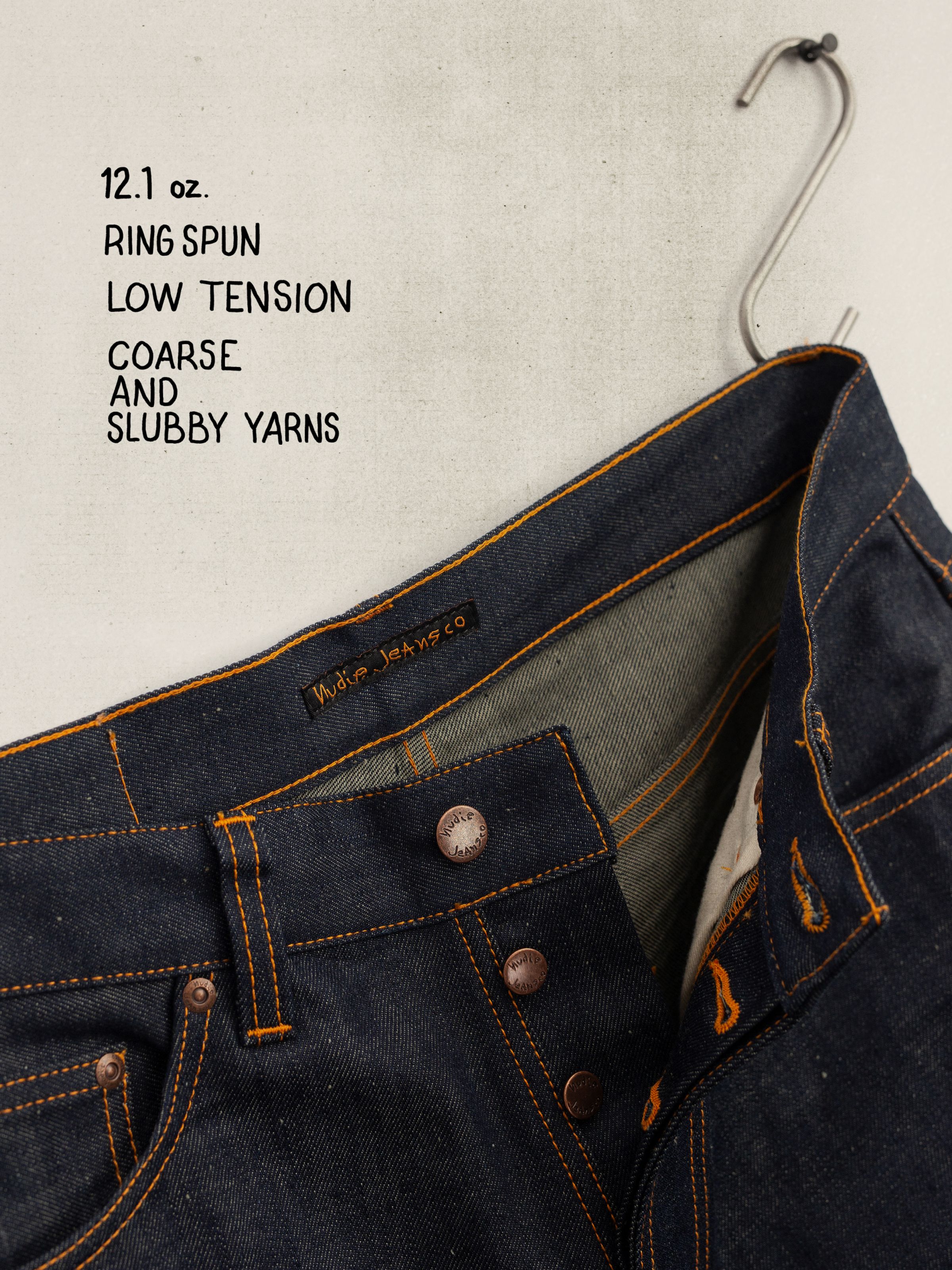 Nudie Jeans Rad Rufus Dry Weird, close-up of the button fly and orange stitching on rigid 12.1 oz dry blue denim.