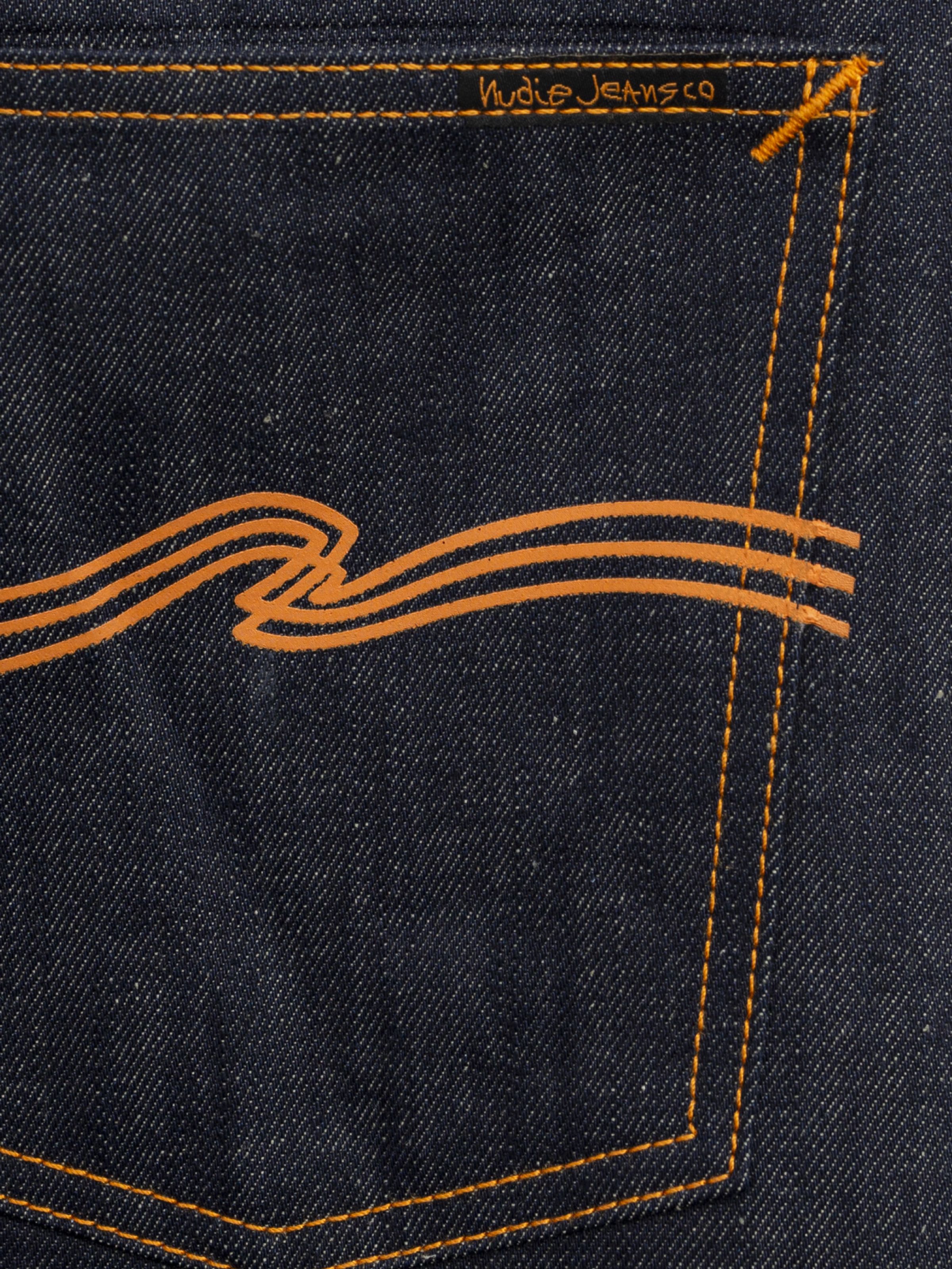 Nudie Jeans Rad Rufus Dry Weird, close-up of the orange printed embo and contrast orange stitching on dark dry denim.