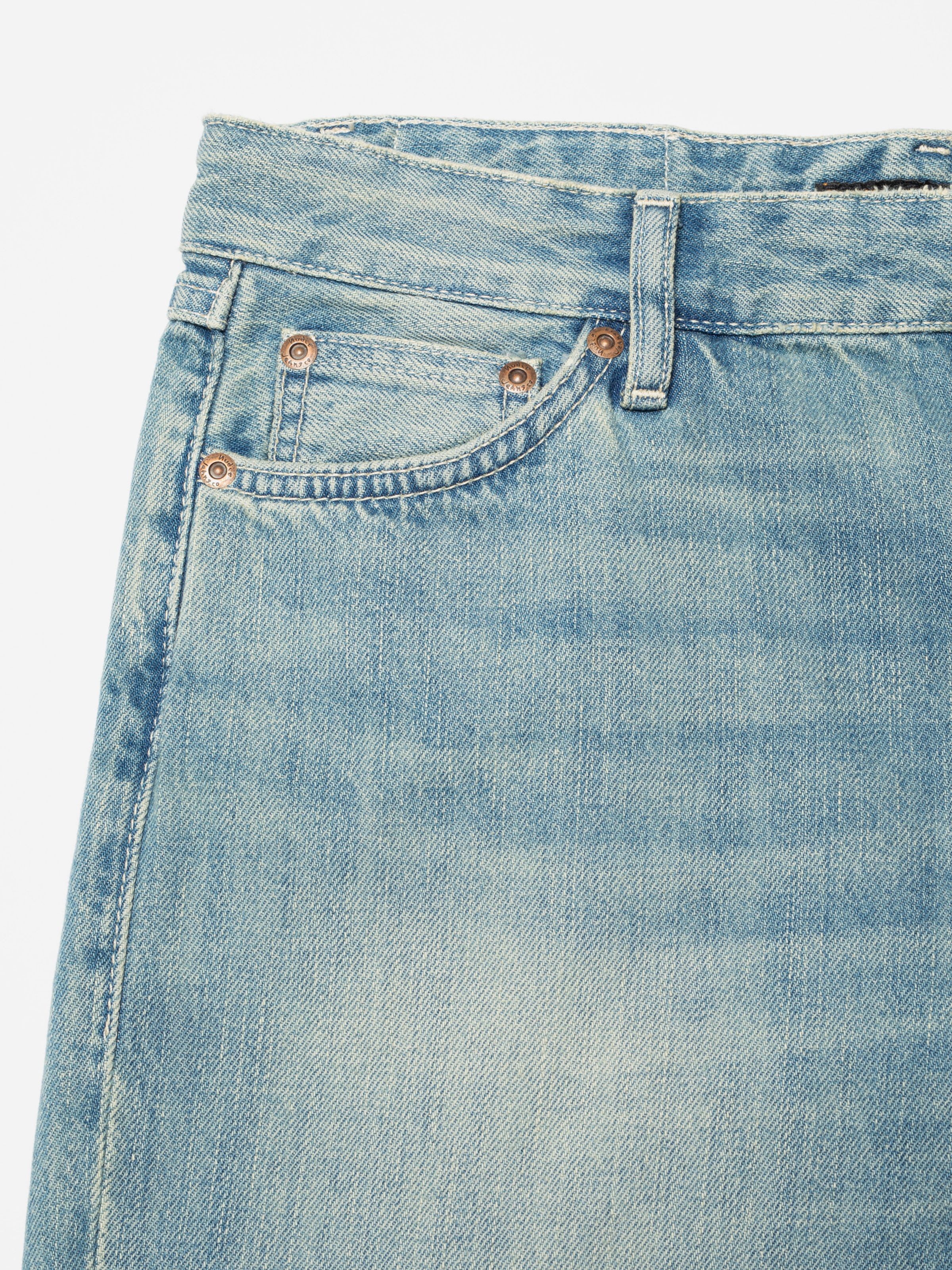 Nudie Jeans Wide Heidi Drift Wood, close-up of the front pocket and copper rivets on light blue denim.