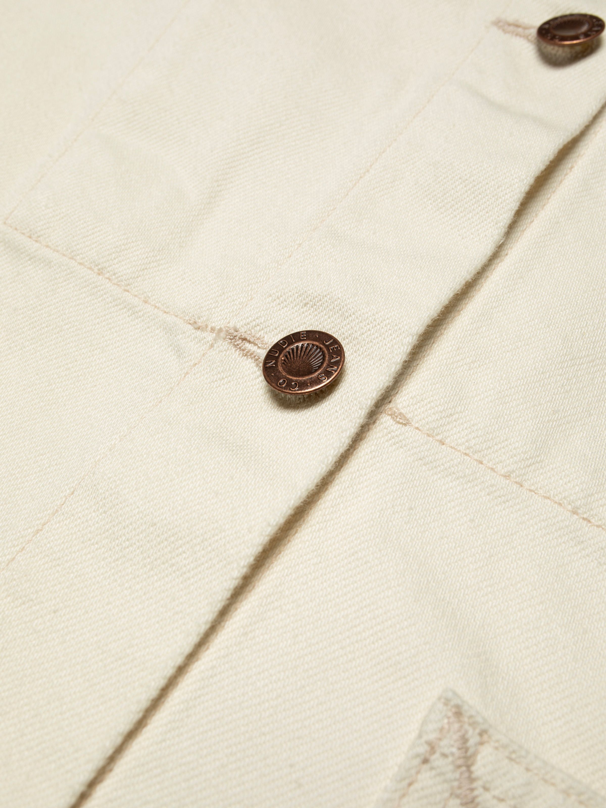 Nudie Jeans Ada Workwear Jacket Ivory, close-up of the vintage-inspired copper button and ivory denim fabric.