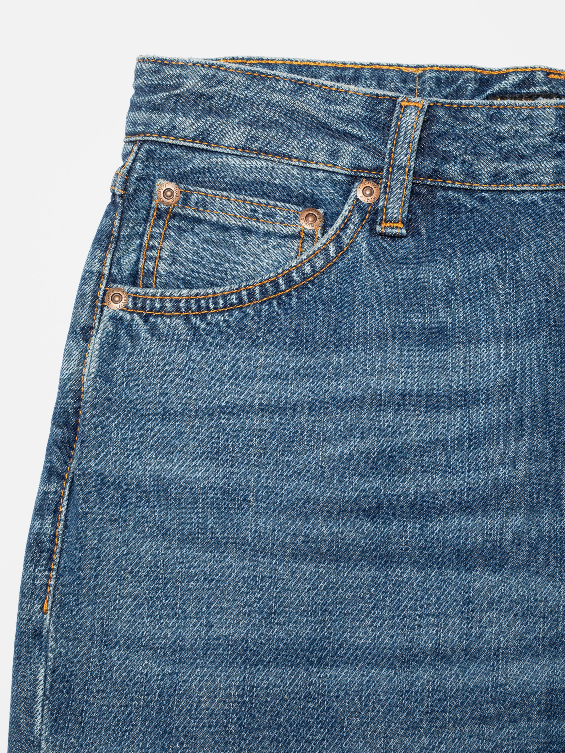 Nudie Jeans Dusty Dee Sierra Sun, close-up of the front pocket area with orange stitching and copper rivets.