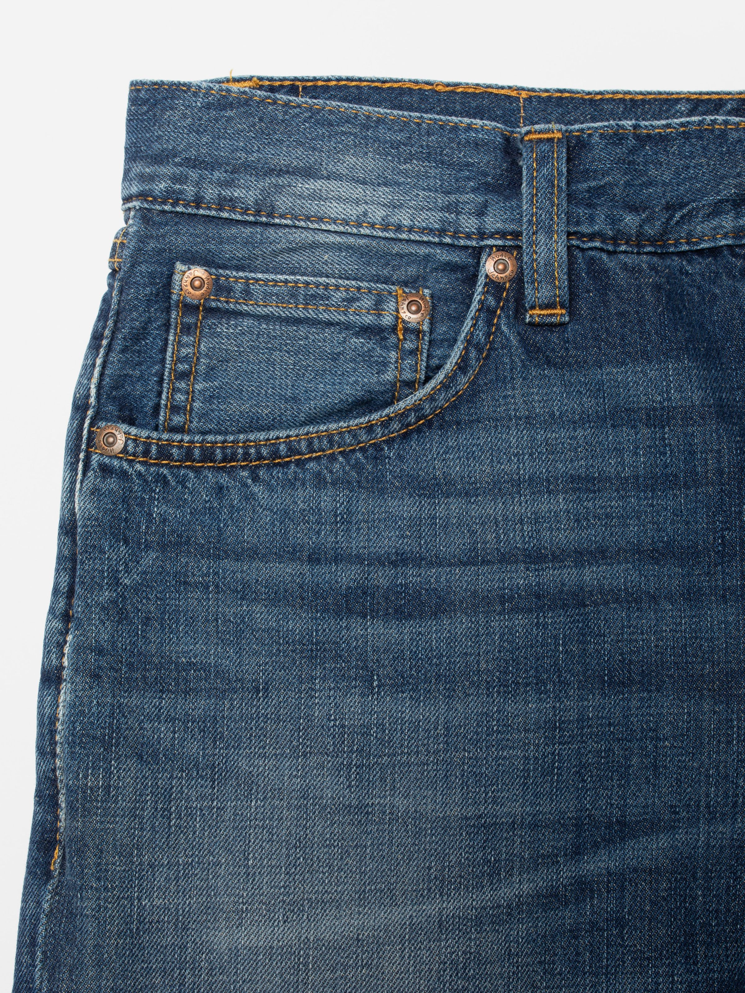 Nudie Jeans Gritty Jackson Sun Set, close-up of the front pocket and copper trims on mid-blue denim.
