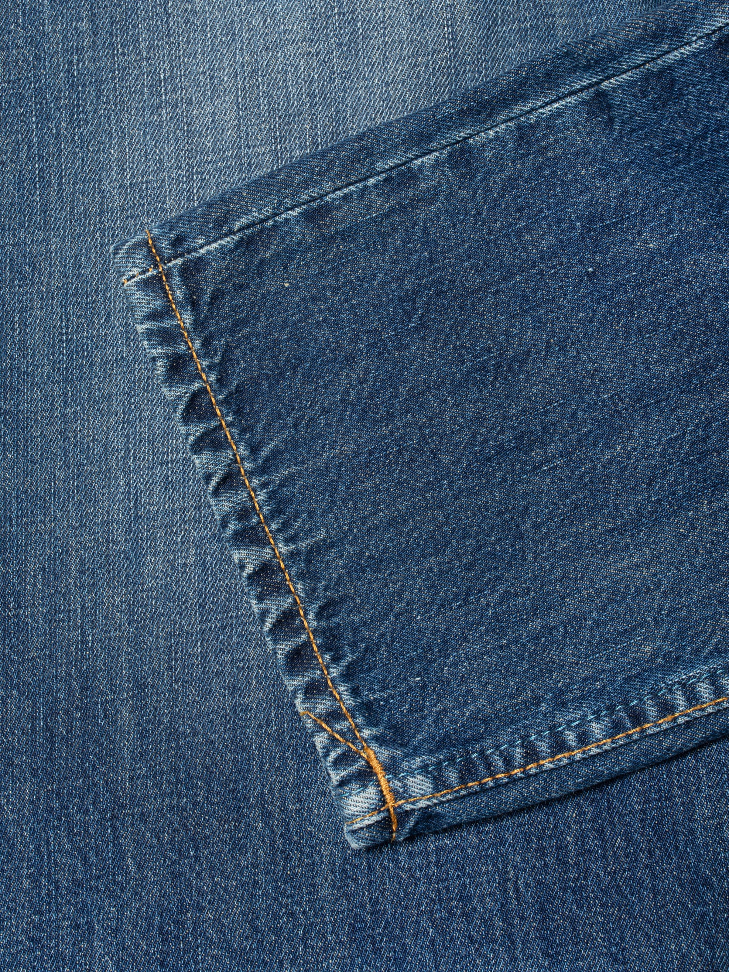 Nudie Jeans Gritty Jackson Sun Set, close-up of the leg opening showing the tobacco thread and mid-blue wash.