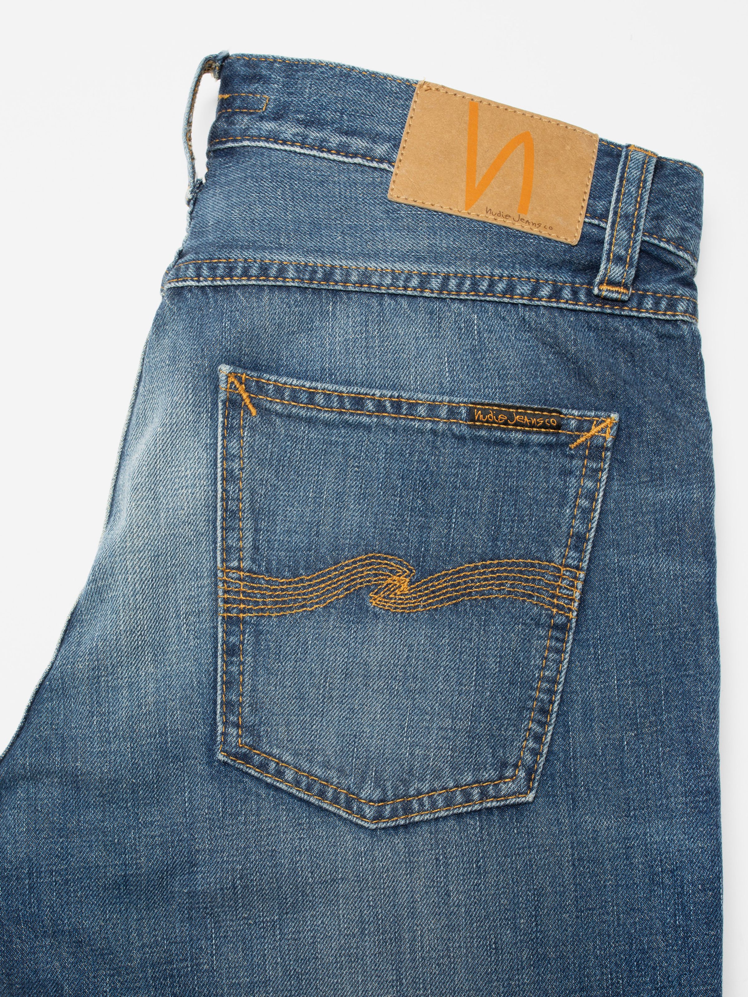 Nudie Jeans Gritty Jackson Sun Set, close-up of the back pocket with orange embroidery and tan Jacron patch.