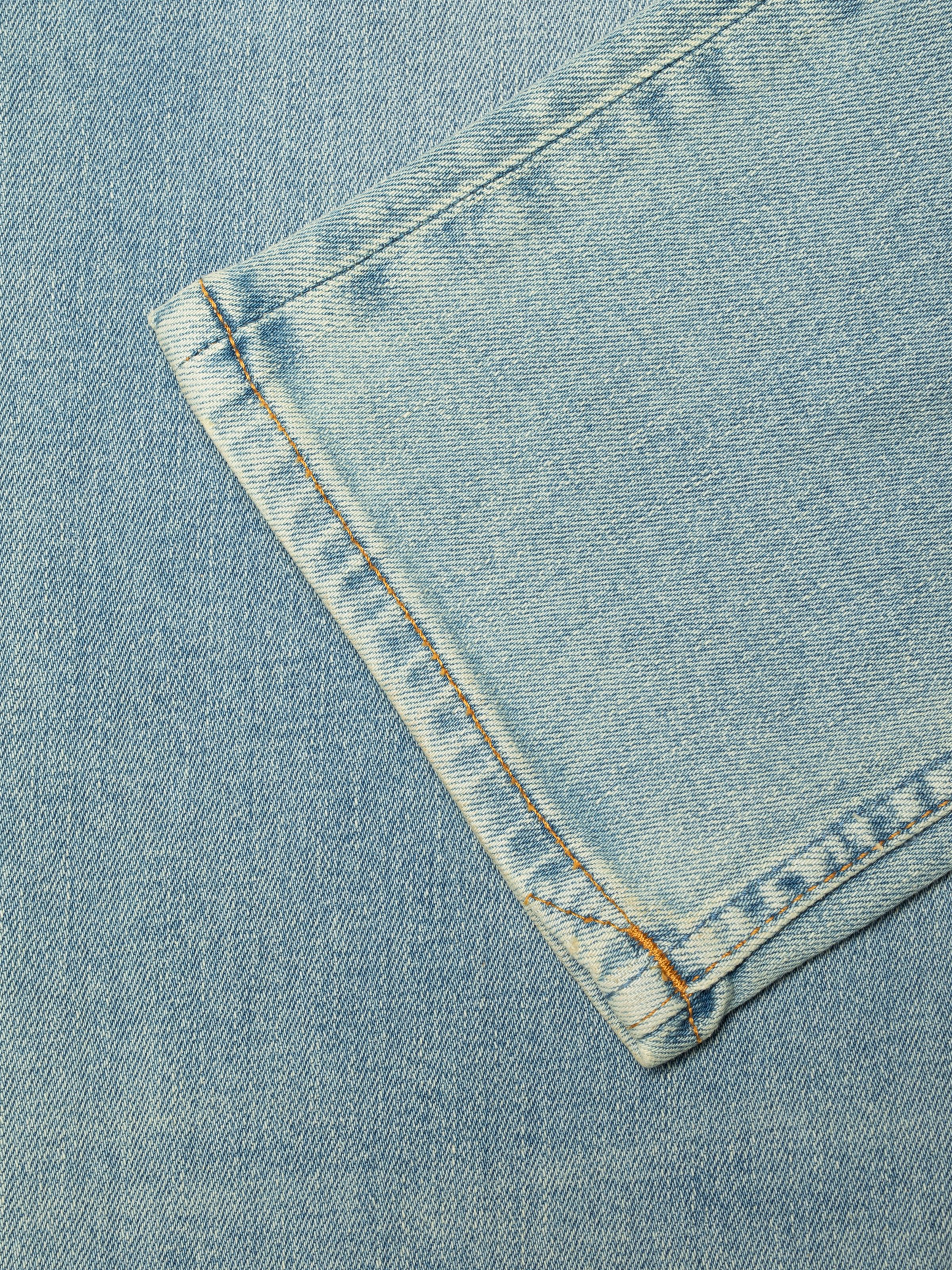 Nudie Jeans Grim Tim Shallow Waters, close-up of the leg opening with tobacco thread stitching on light blue denim.