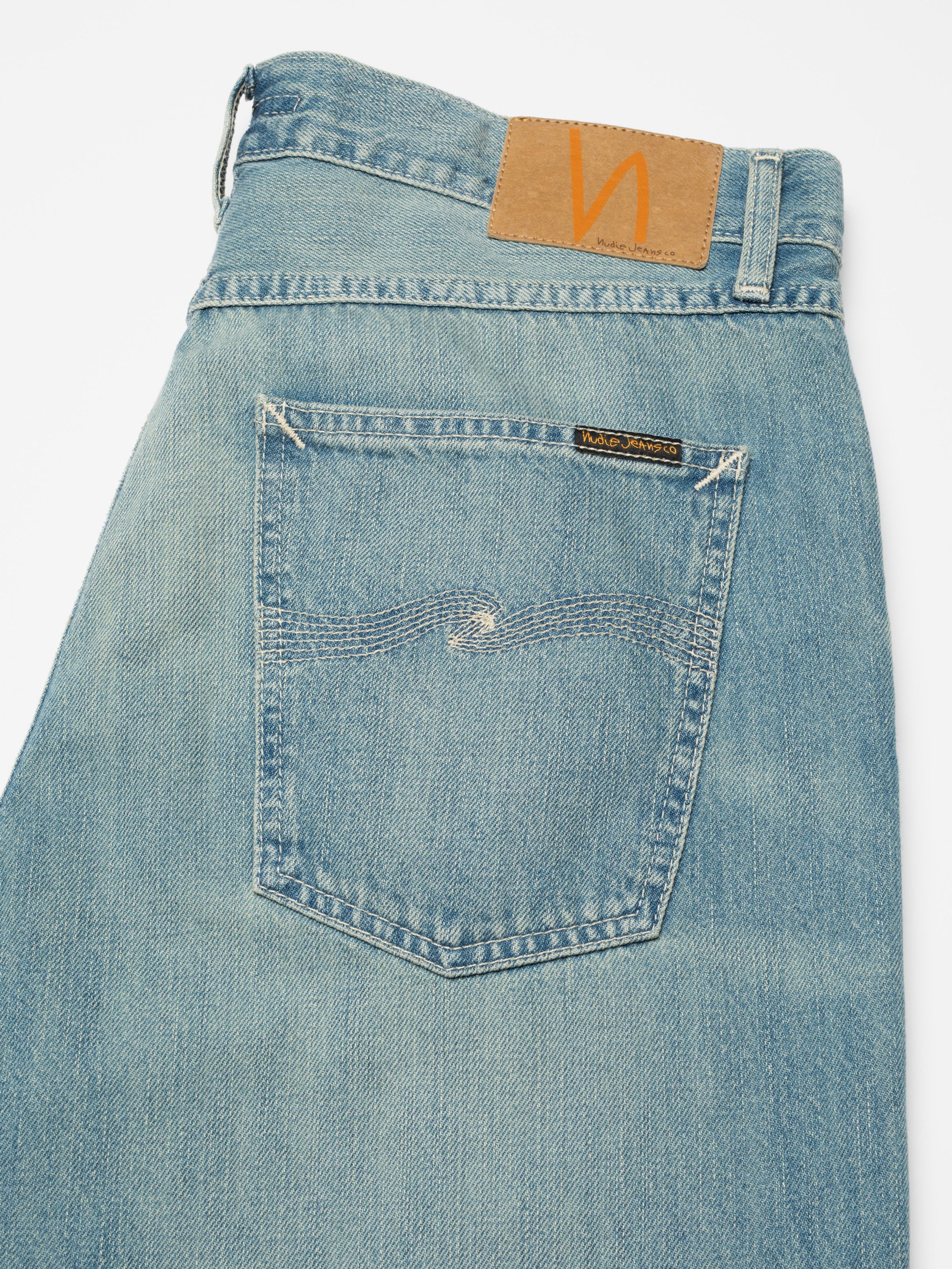 Nudie Jeans Tuff Tony Drift Wood, loose-fit jeans, close-up of back pocket with ecru embroidery and jacron patch.