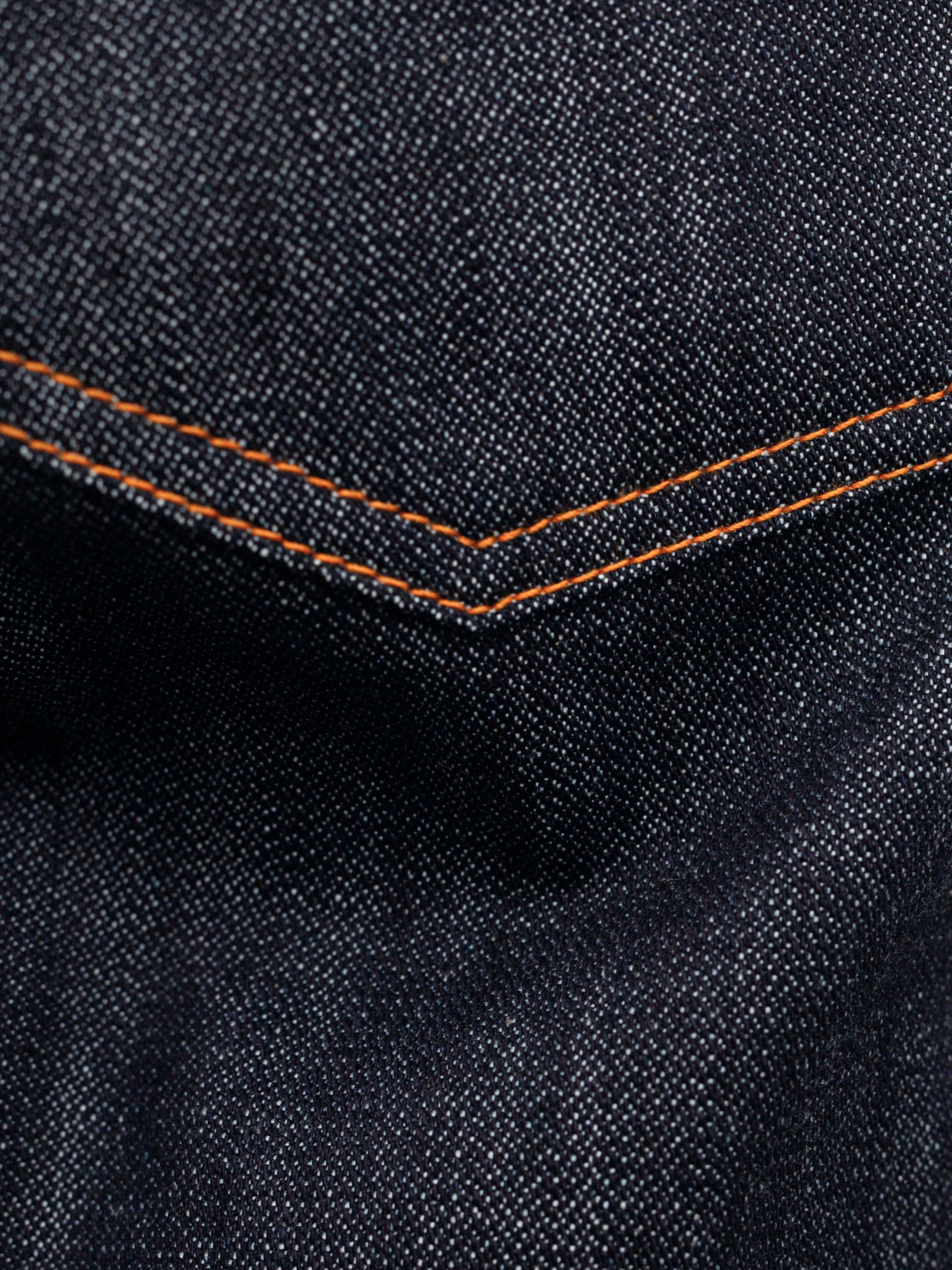 Nudie Jeans Slim Jim Dry Two, close-up of orange stitching on dark indigo rigid organic cotton broken twill denim.