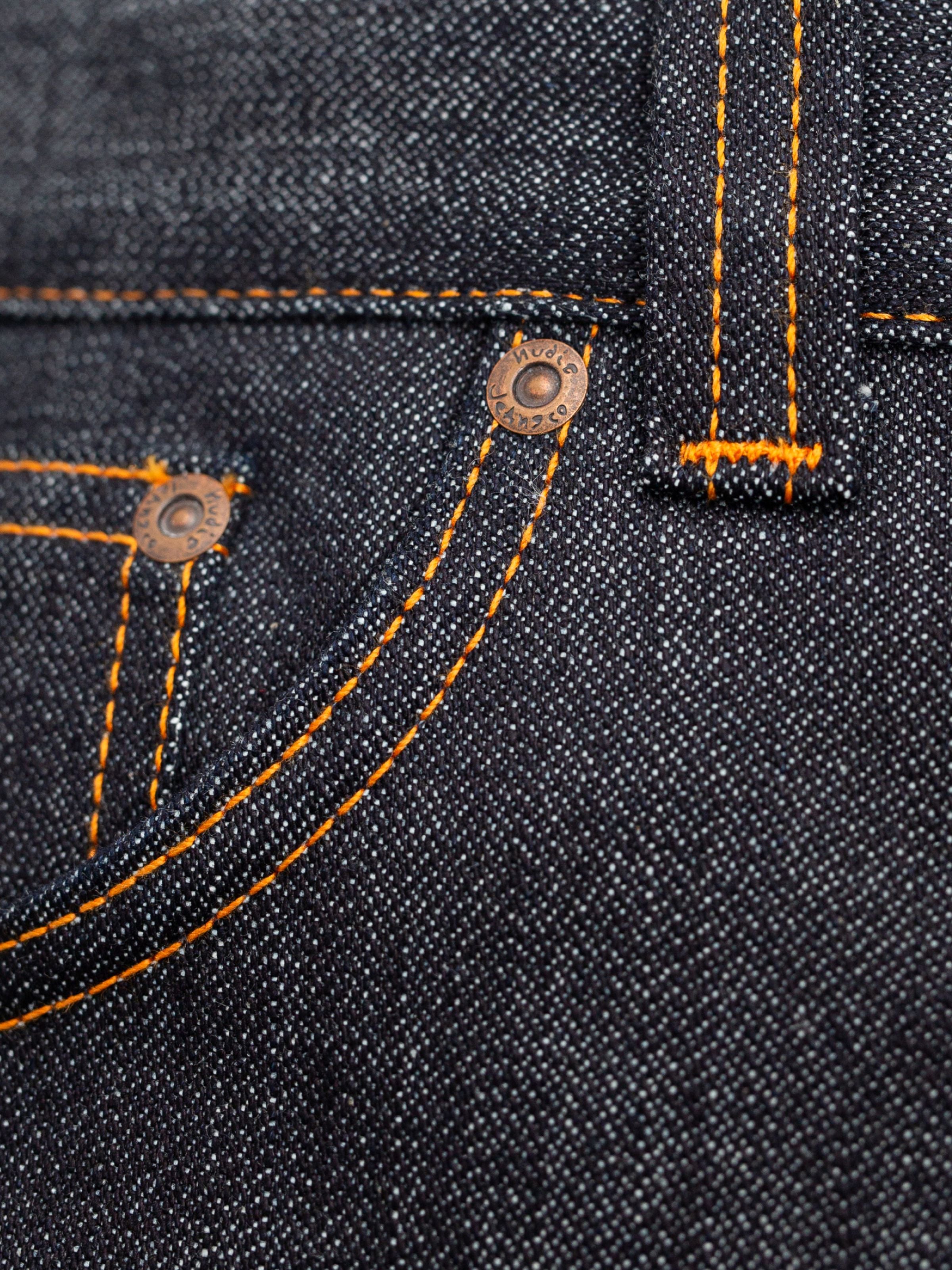 Nudie Jeans Slim Jim Dry Two, a close-up of the orange stitching and copper rivets on rigid indigo organic cotton denim.