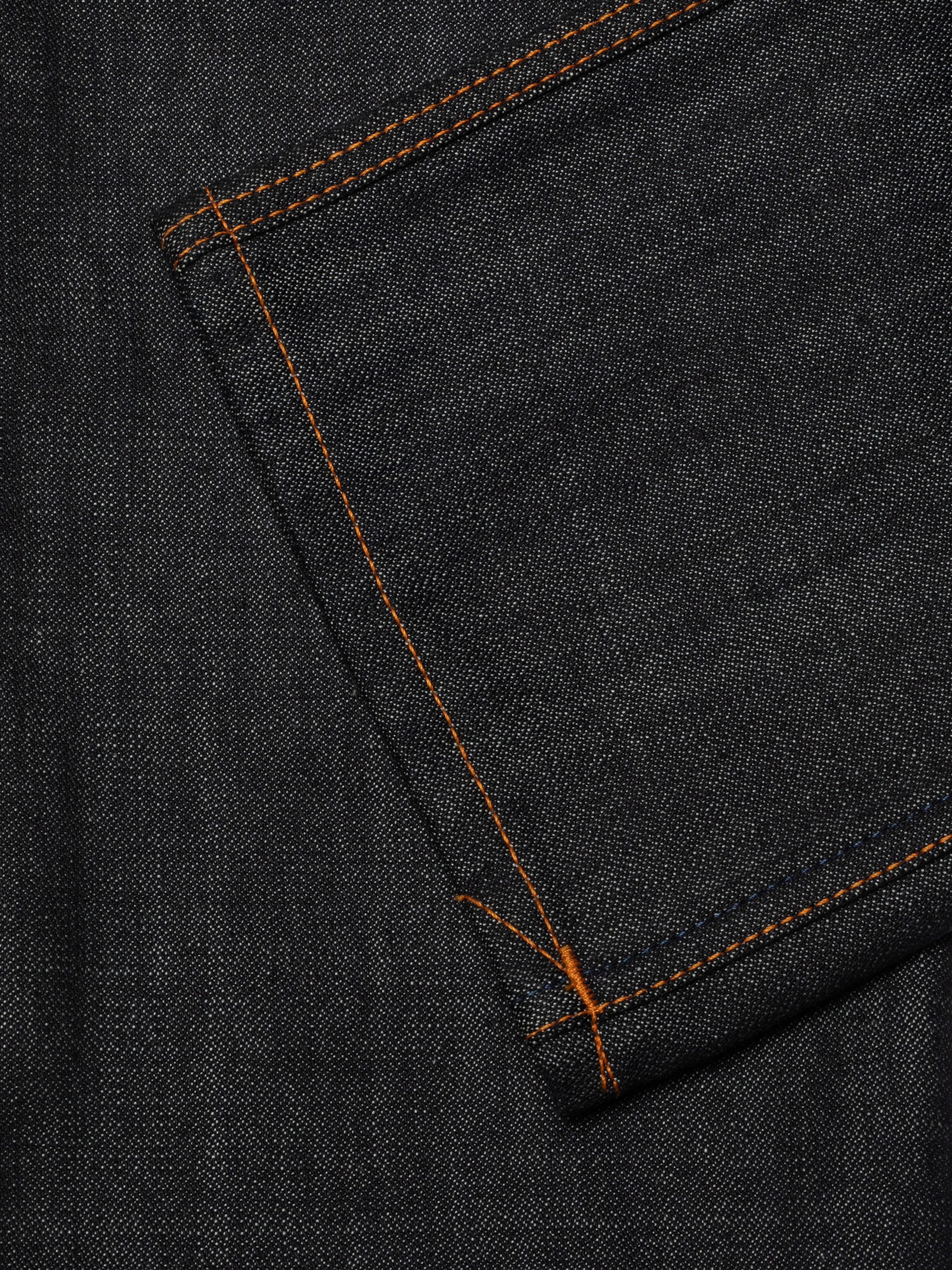 Nudie Jeans Slim Jim Dry Two, close-up of the back pocket with orange contrast stitching on dark indigo rigid denim.