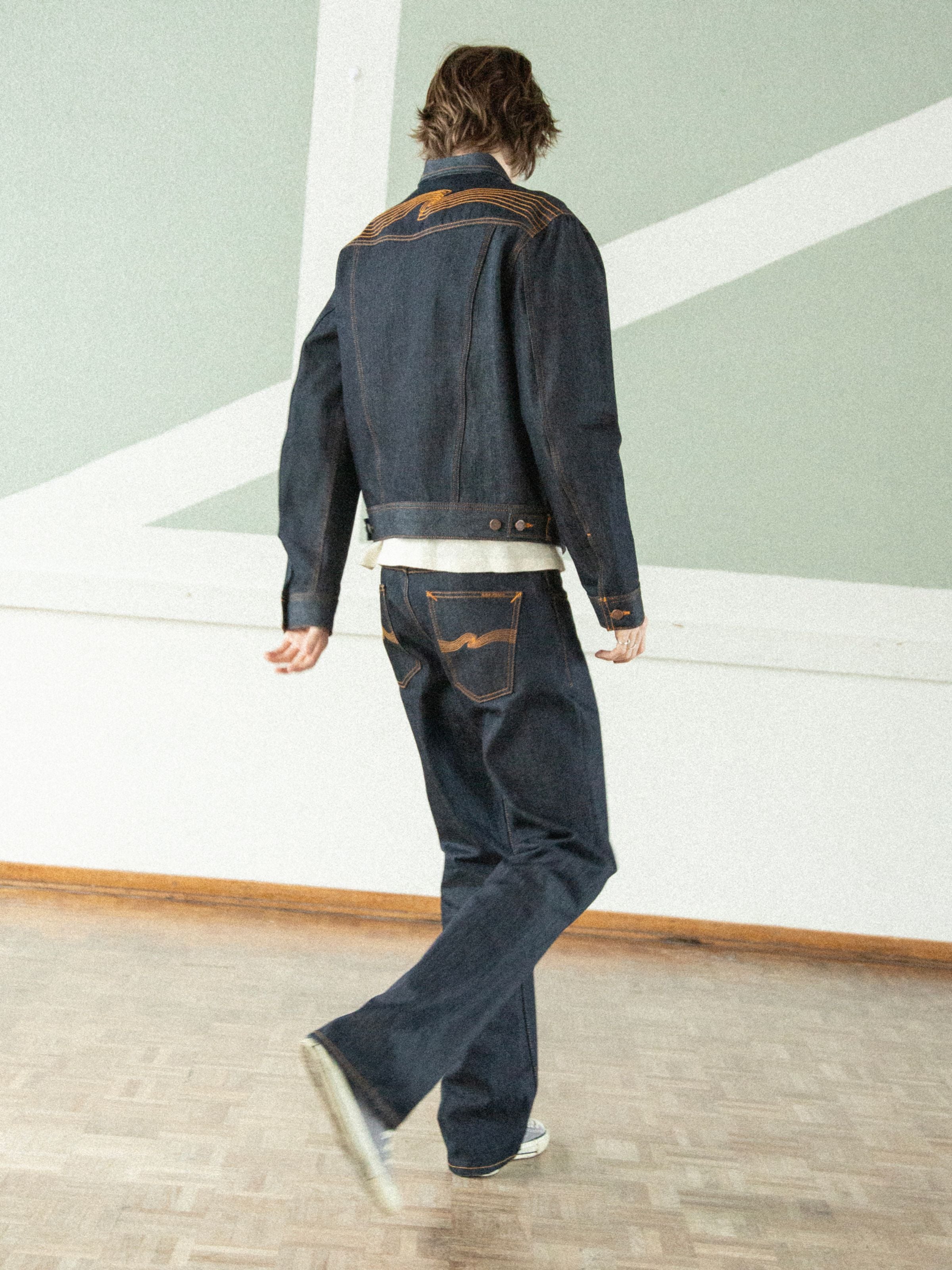 Nudie Jeans Regular Alf Dry One, rigid indigo organic cotton bootcut jeans and matching jacket, shown from behind on a model.