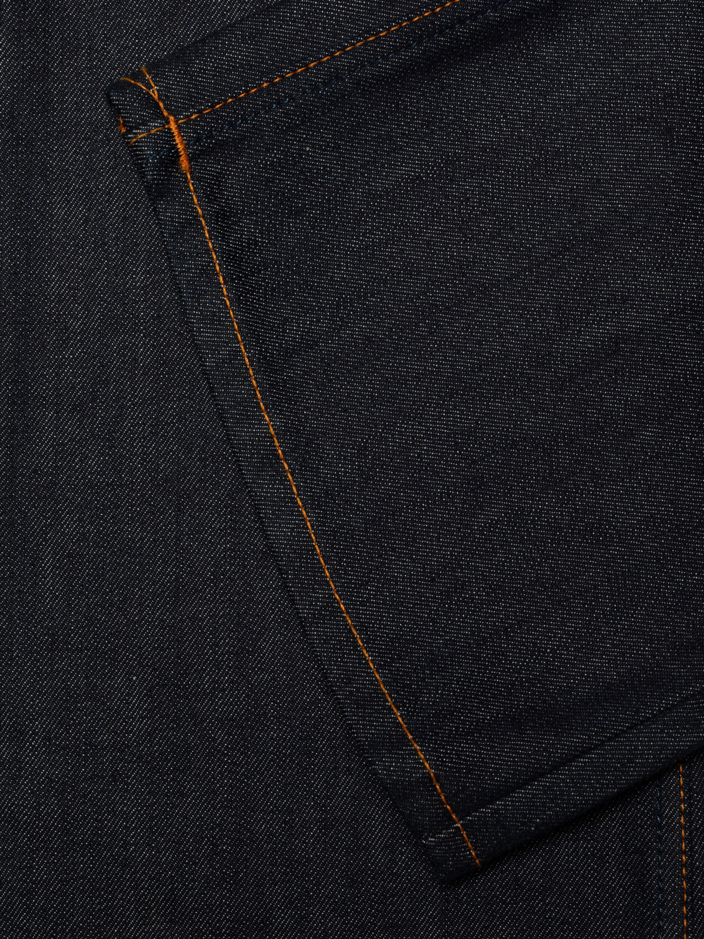 Nudie Jeans Regular Alf Dry One, close-up of the 13.5 oz. rigid indigo denim showing orange thread at the seams.