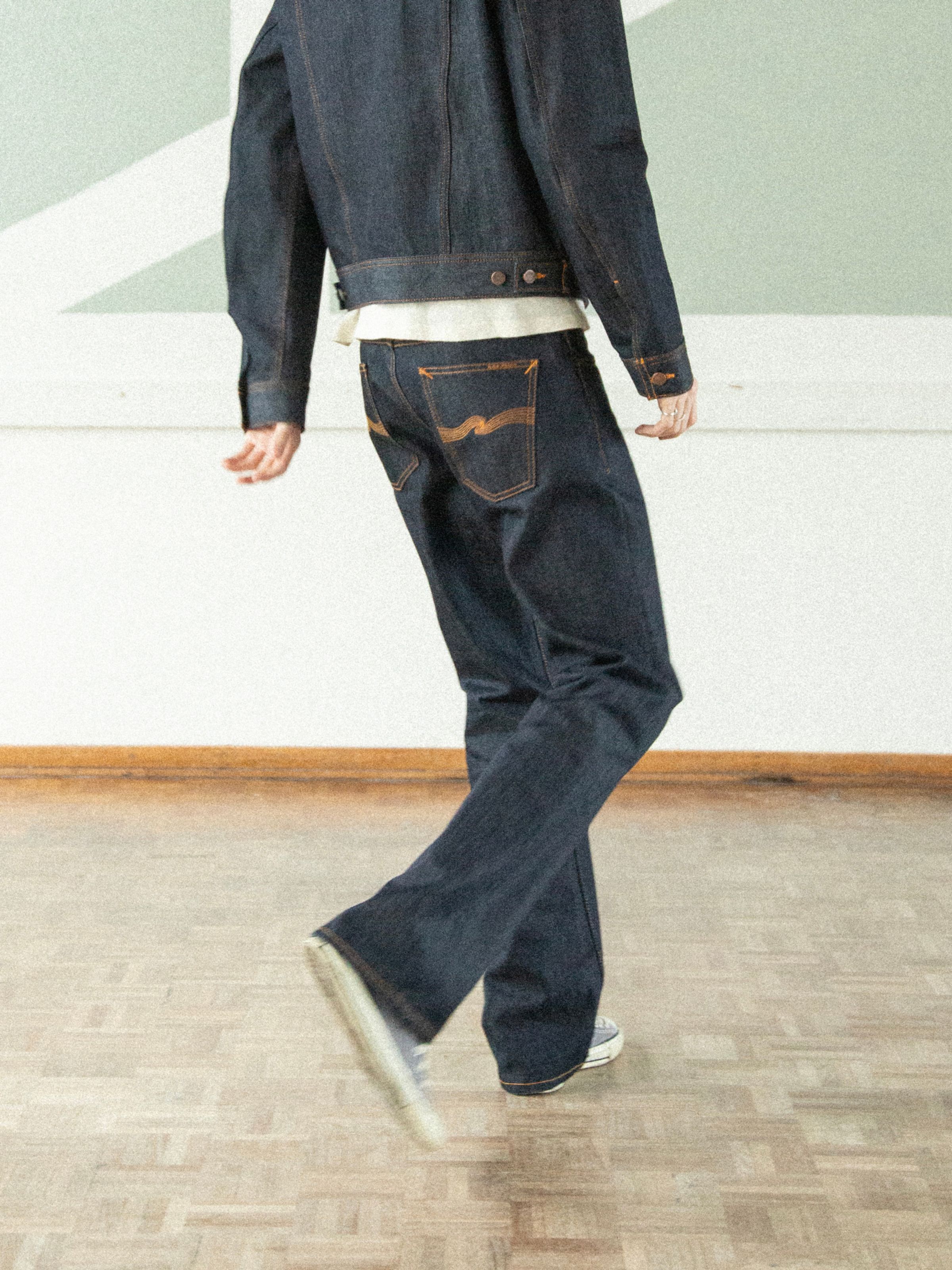 Nudie Jeans Regular Alf Dry One bootcut jeans in rigid dry blue denim with orange stitching, back view on a model.