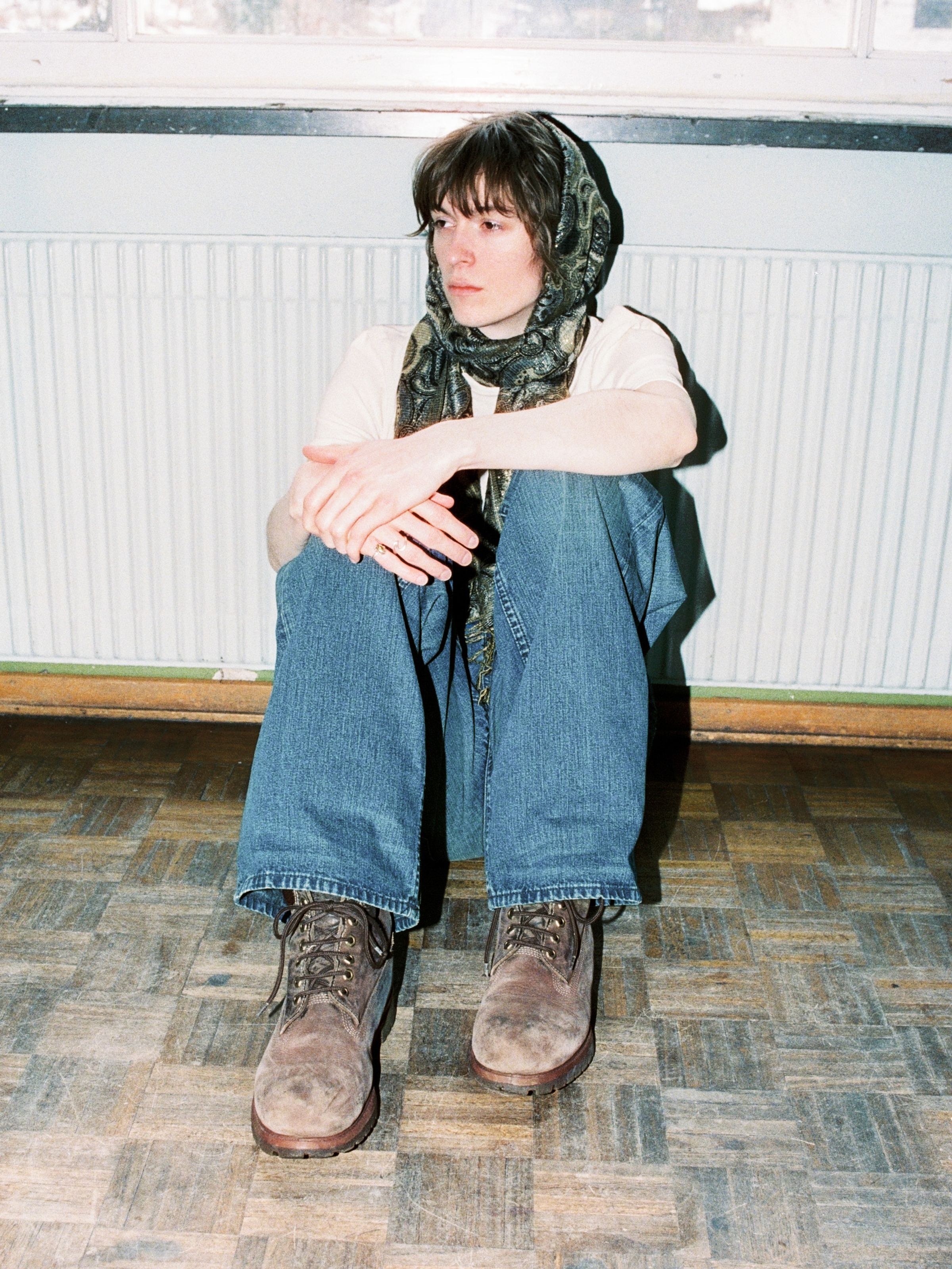 Nudie Jeans Loud Larry Blue Painter, loose-fit wide-leg jeans shown on a model sitting on the floor.