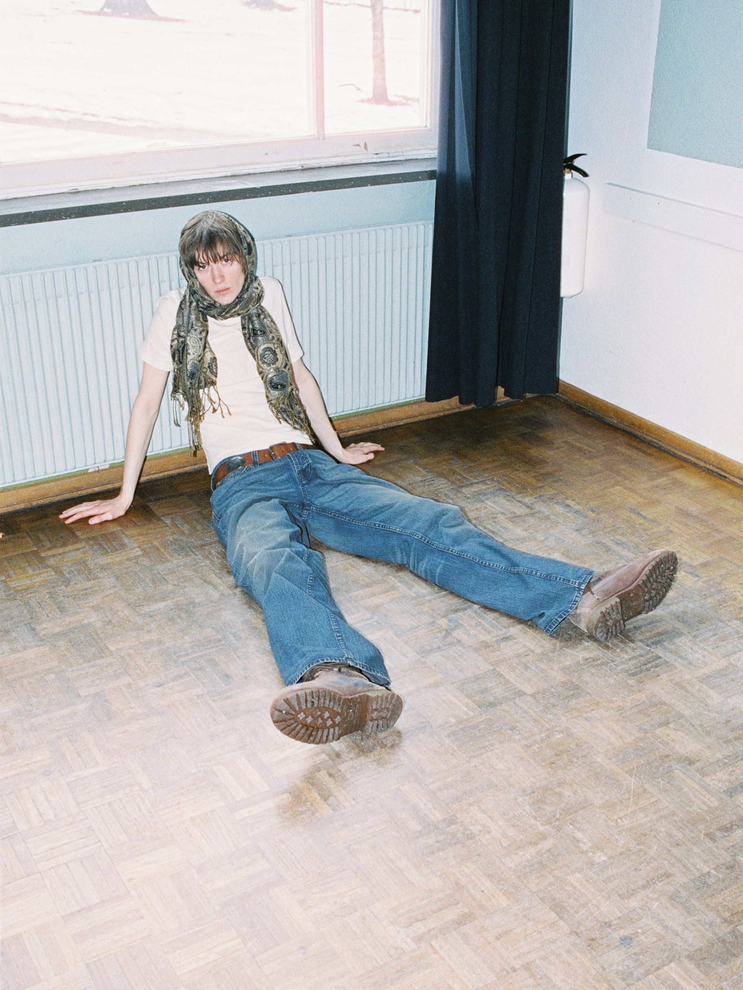 Nudie Jeans Loud Larry Blue Painter, men's loose-fit wide-leg jeans, shown on a model sitting on a wooden floor.