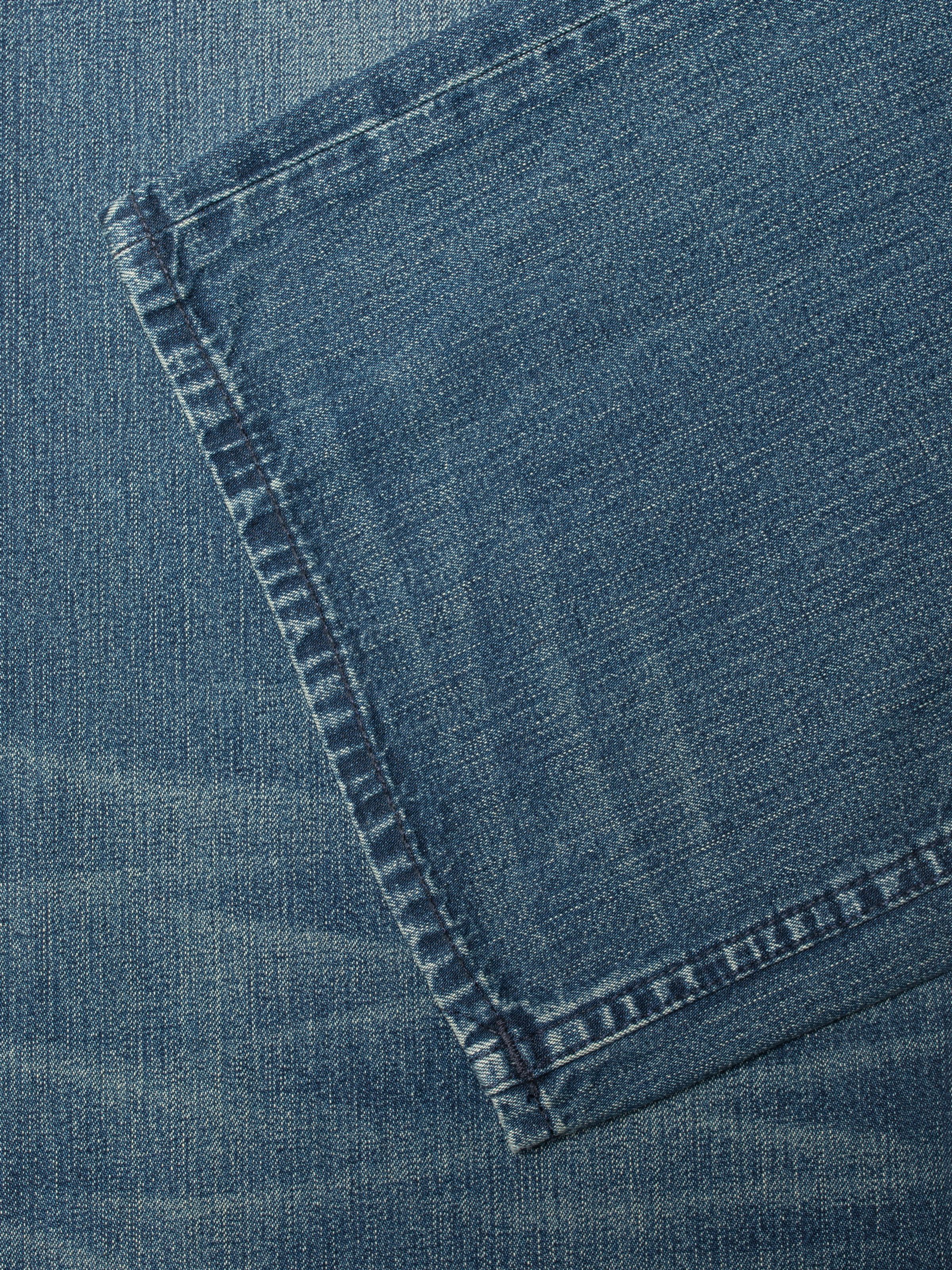 Nudie Jeans Loud Larry Blue Painter, close-up of the blue denim texture and navy blue stitching.