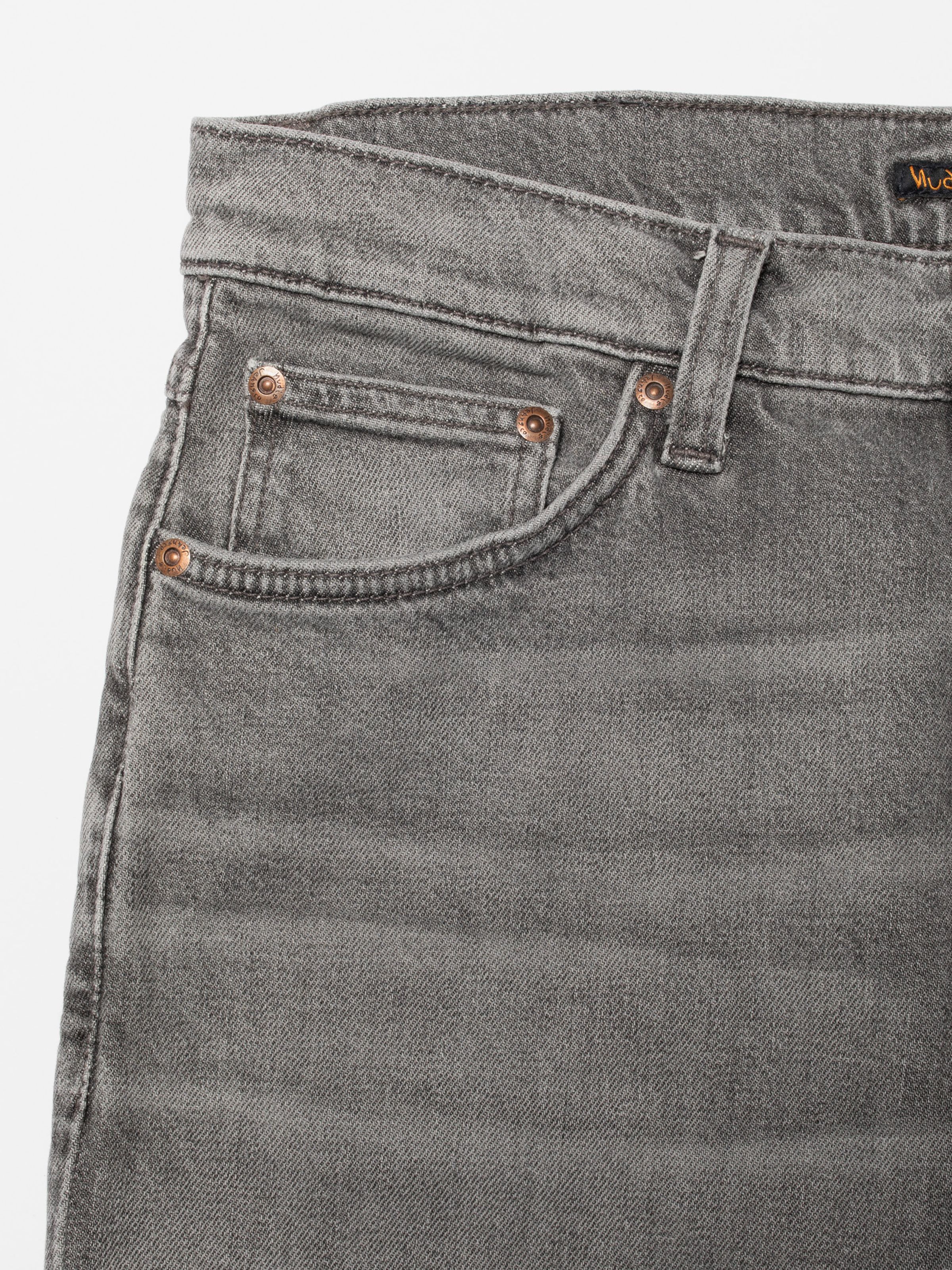 Nudie Jeans Solid Ollie Pale Ash, close-up of the front pocket and copper rivets on grey wash denim.