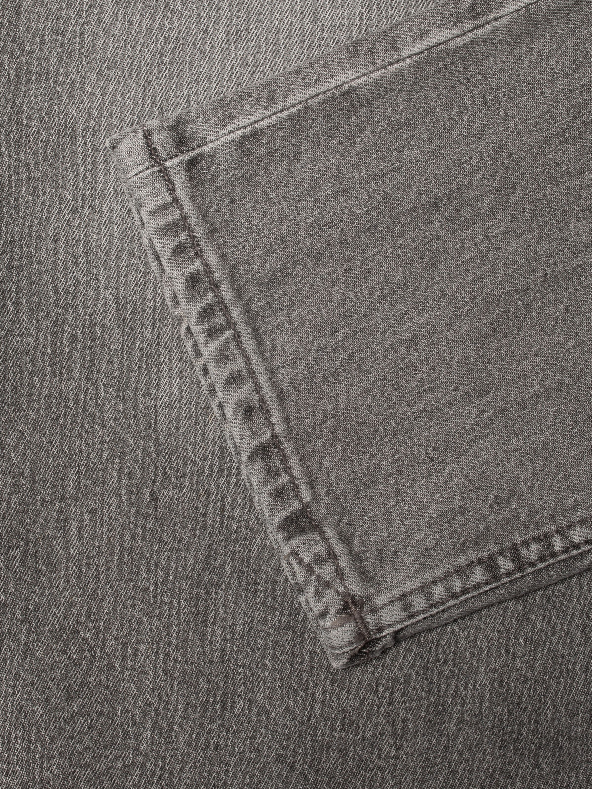 Nudie Jeans Solid Ollie Pale Ash, close-up of the grey denim fabric and tonal grey stitching.