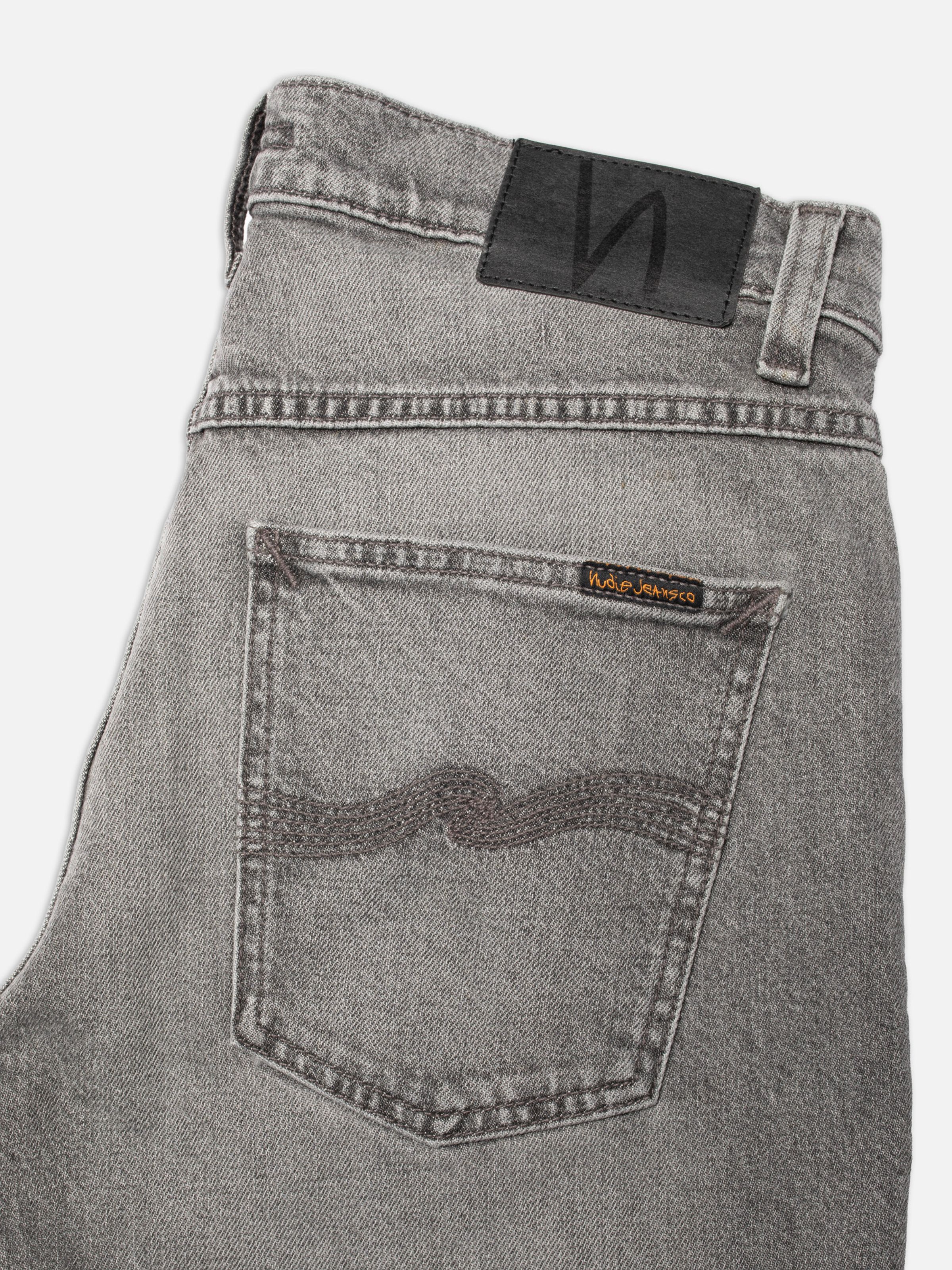 Nudie Jeans Solid Ollie Pale Ash, close-up of the back pocket and black Jacron patch on pale grey denim.