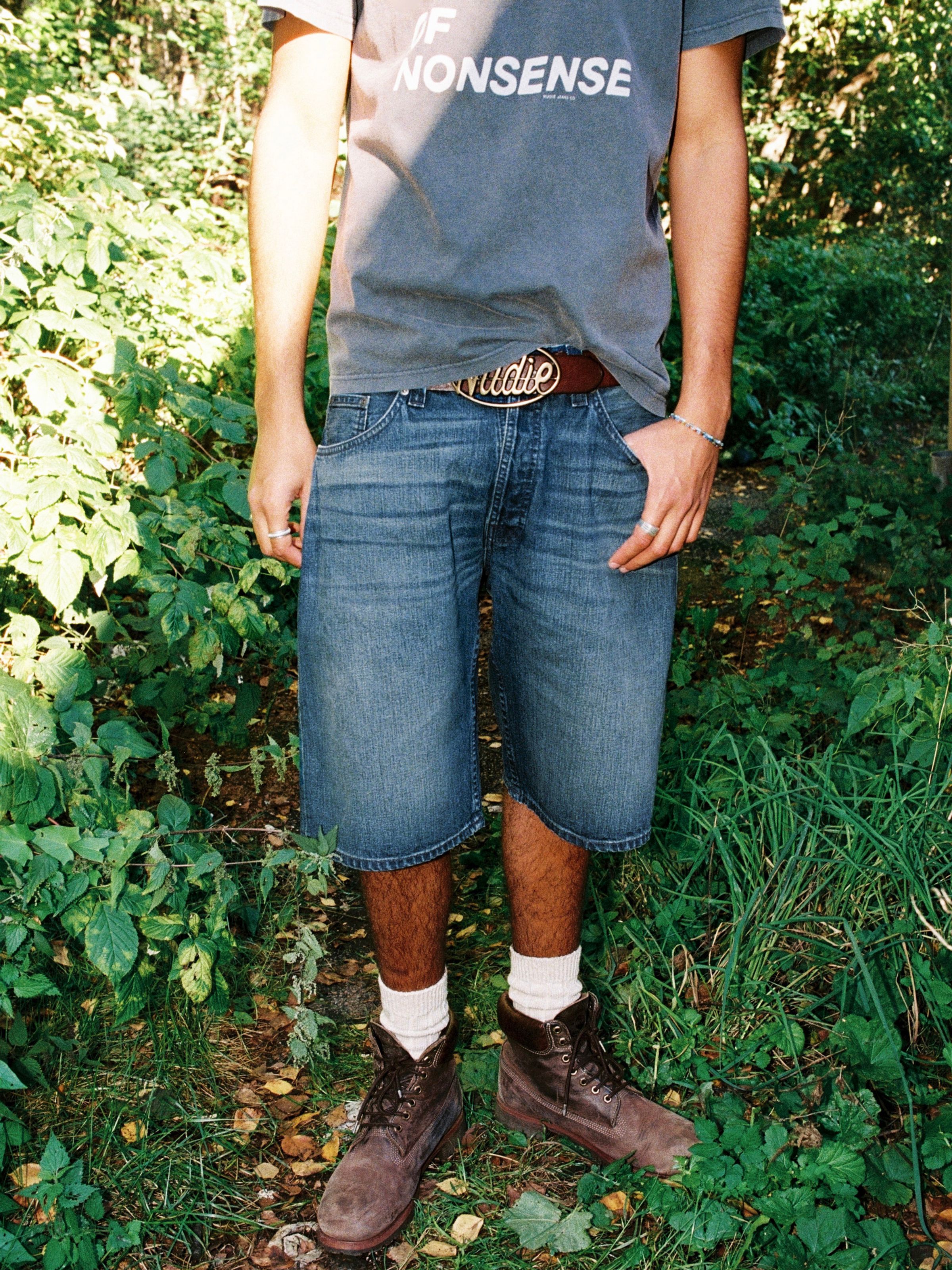 Nudie Jeans Zeb Denim Shorts Blue Painter, men's wide-leg denim shorts shown on a model in an outdoor setting.