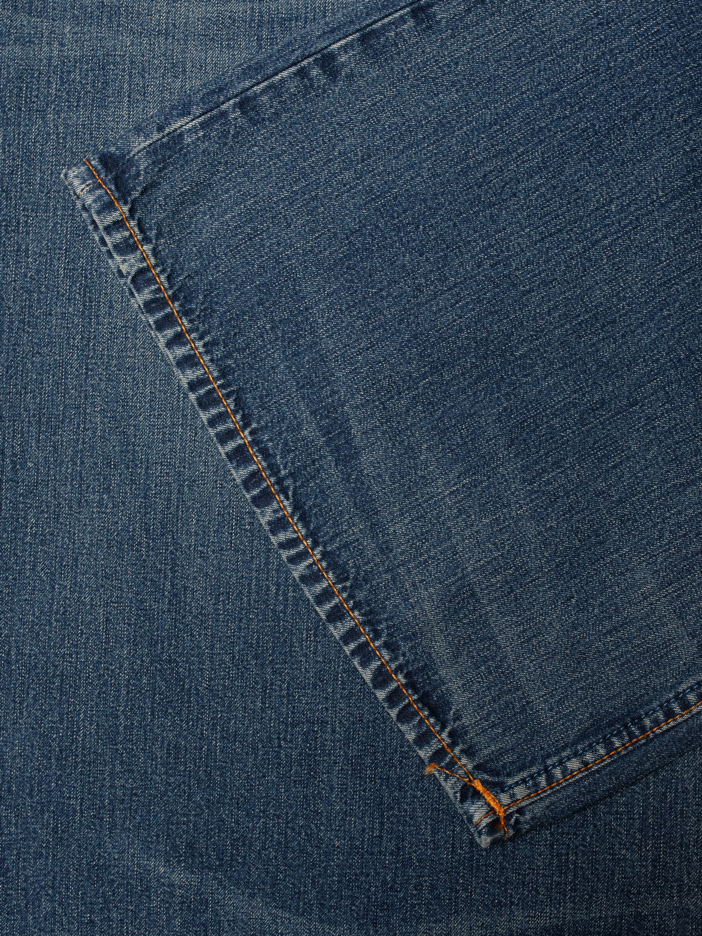 Nudie Jeans Sonic Sue Orange Painter, close-up of the mid blue denim fabric and orange thread stitching.
