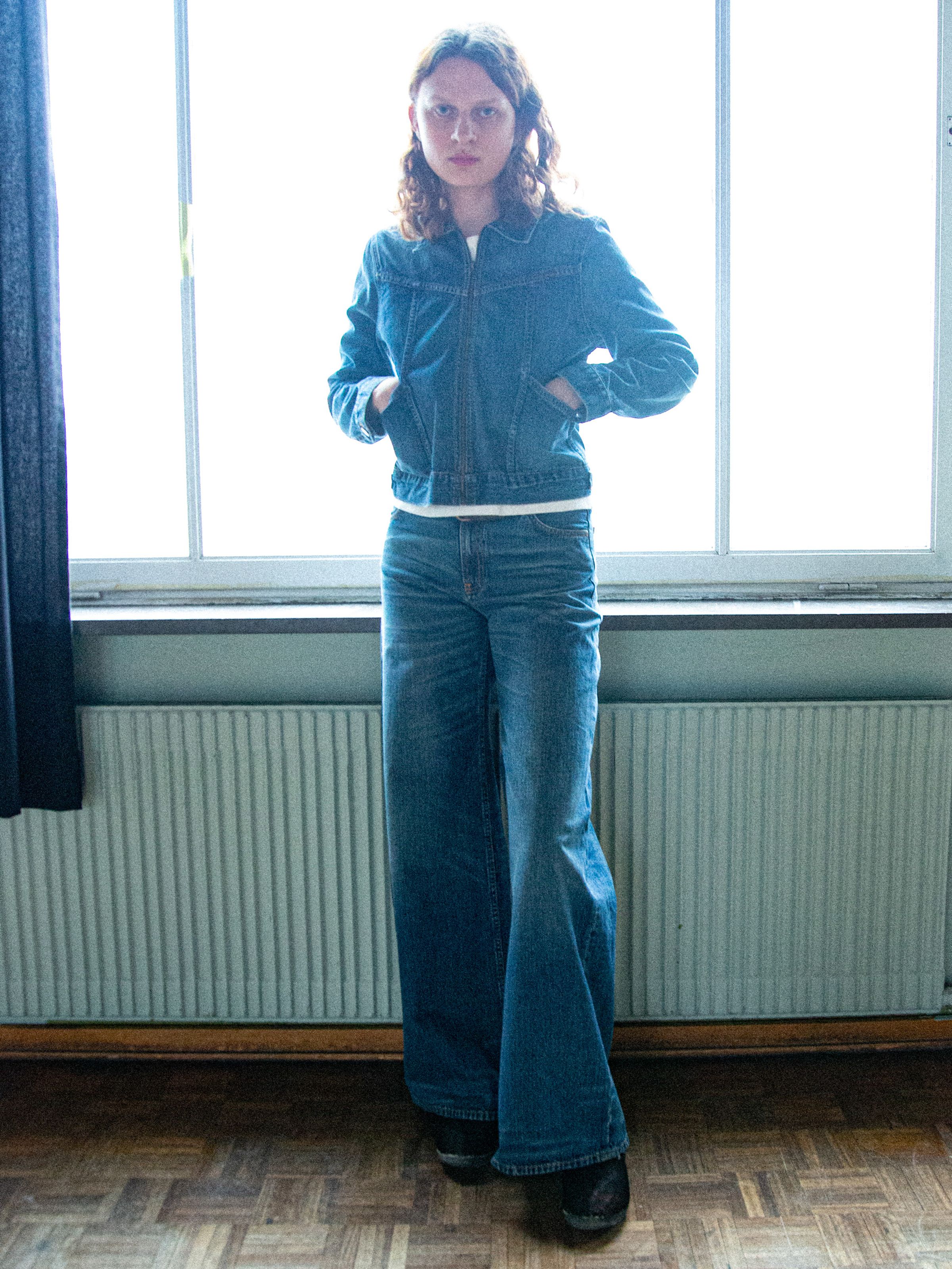 Nudie Jeans Sonic Sue Orange Painter, women's wide-leg jeans and jacket shown on a model in a lifestyle setting.