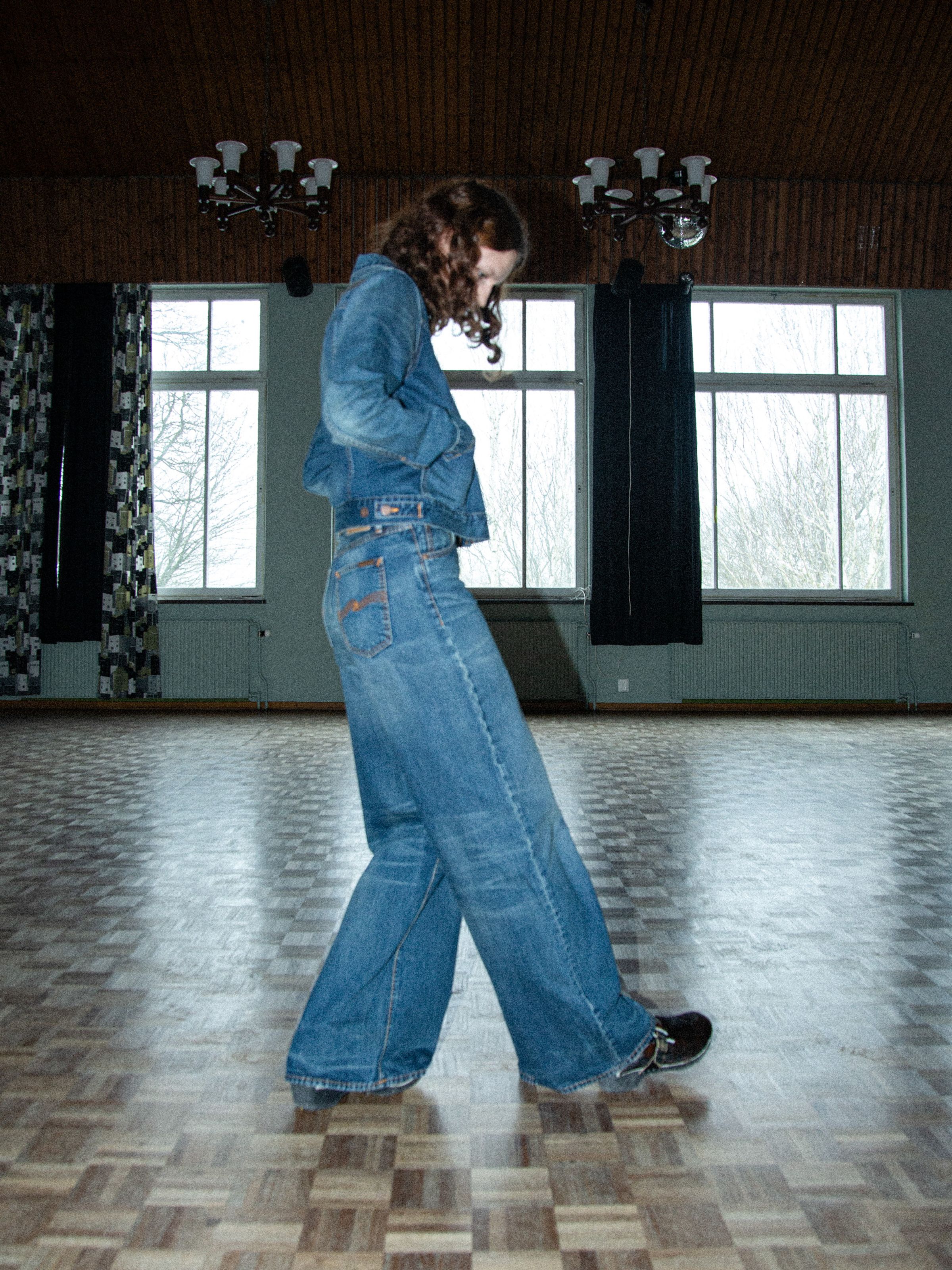 Nudie Jeans Sonic Sue Orange Painter, women's loose-fit wide-leg jeans shown from the side on a model.