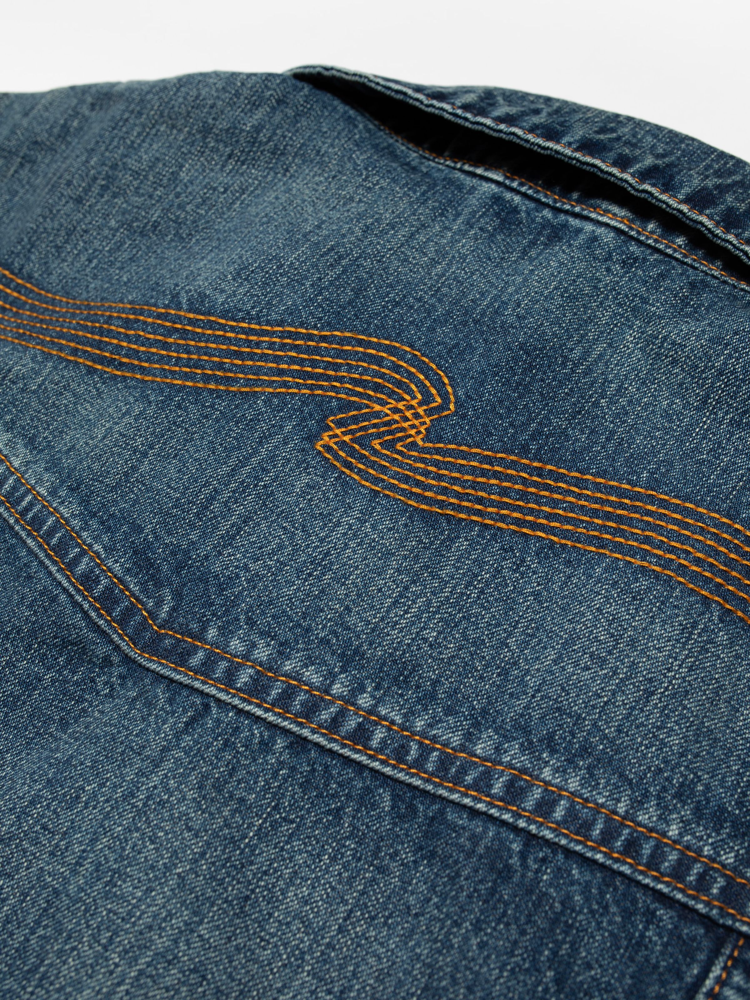 Nudie Jeans Britta Jacket Orange Painter, close-up of the orange embroidery on the mid-blue denim.
