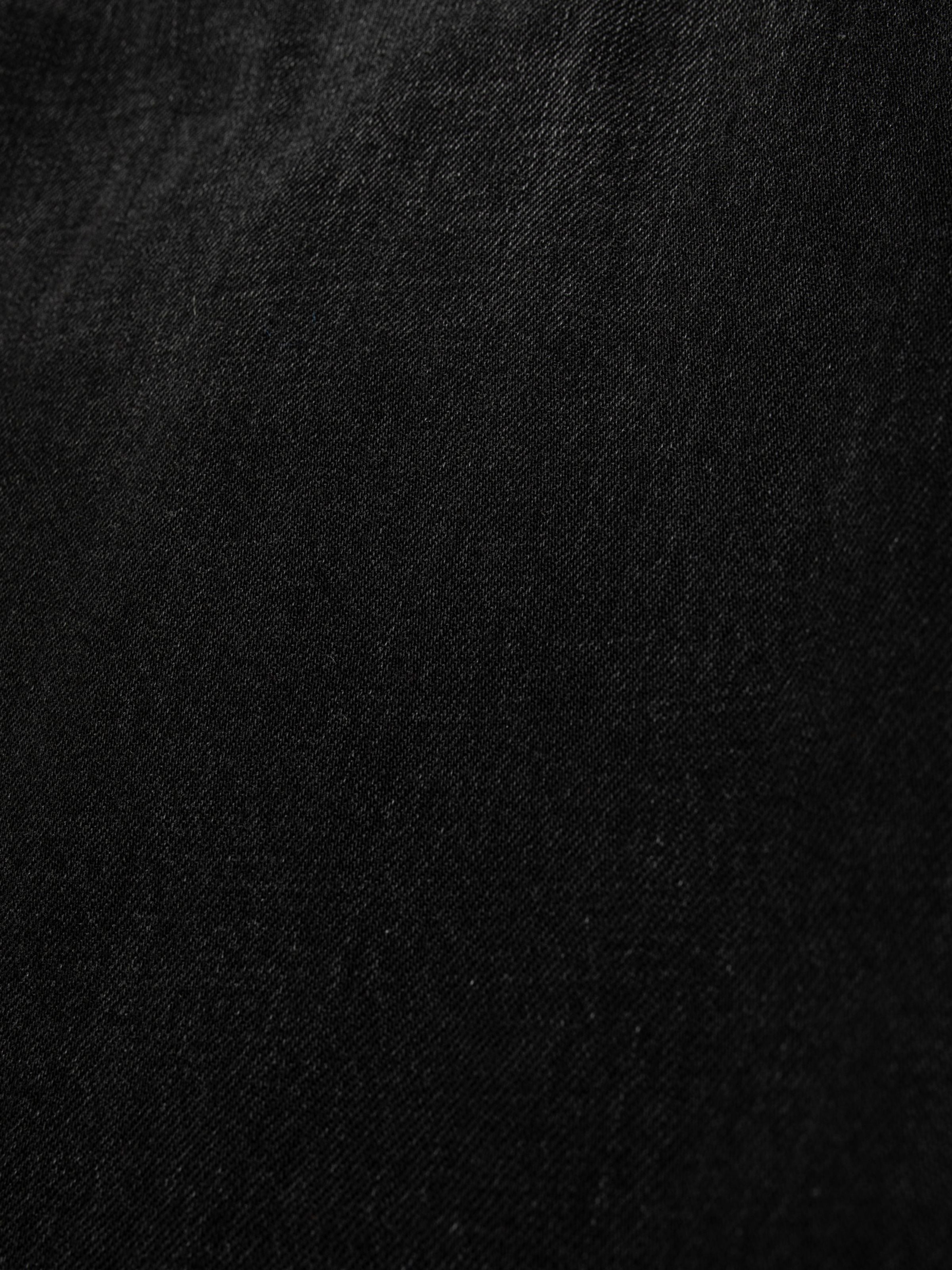 Nudie Jeans Dusty Dee Night Dune, a close-up shot showing the texture of the black rigid denim fabric.