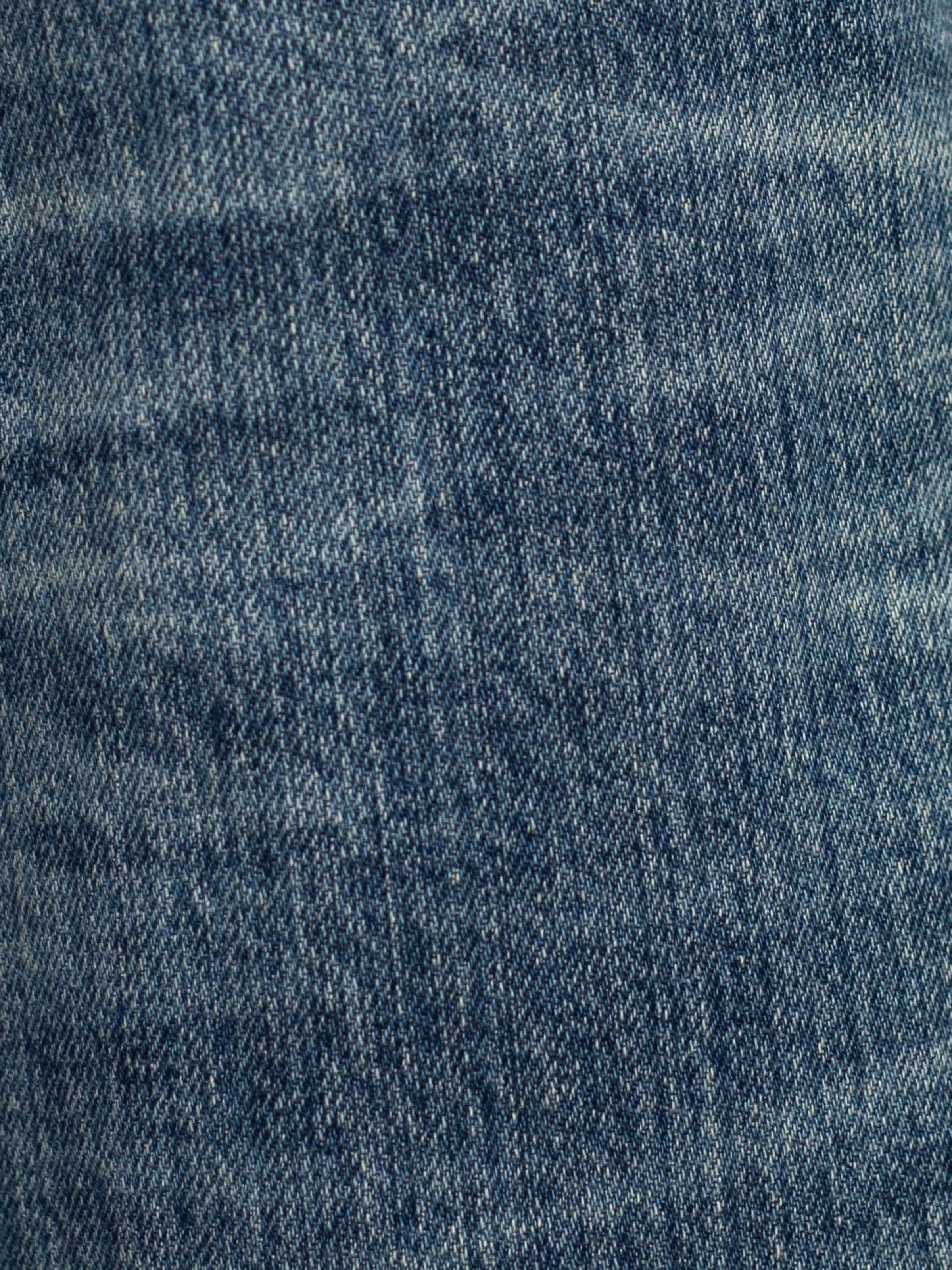 Nudie Jeans Regular Alf Silver Tracks, extreme close-up of the streaky mid blue rigid denim and twill texture.