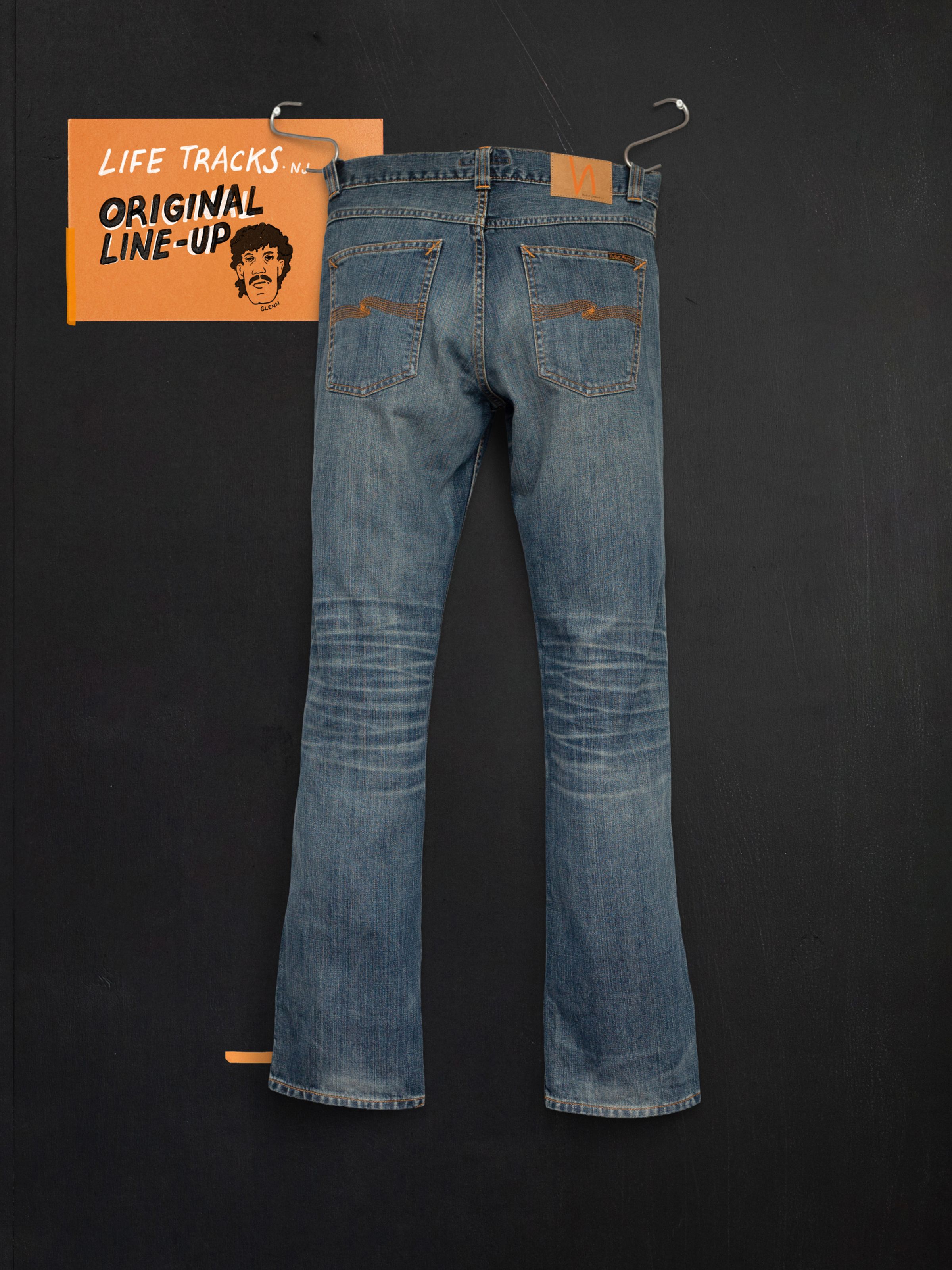 Nudie Jeans Slim Jim Quarter Tracks, mid blue slim-fit organic rigid denim jeans with wear marks, shown from the back.