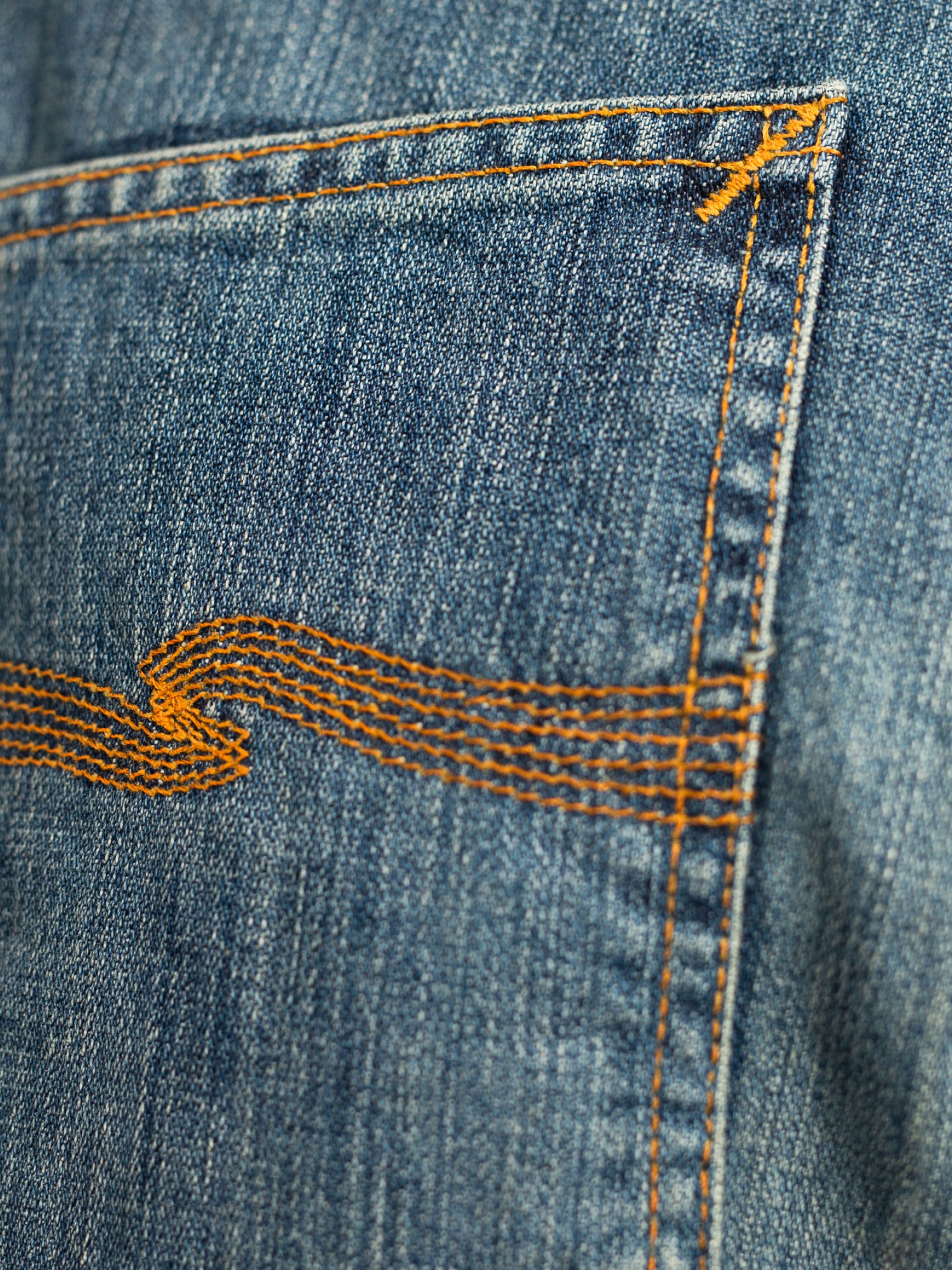 Nudie Jeans Slim Jim Quarter Tracks, close-up of the orange back pocket embroidery on mid blue washed rigid denim.