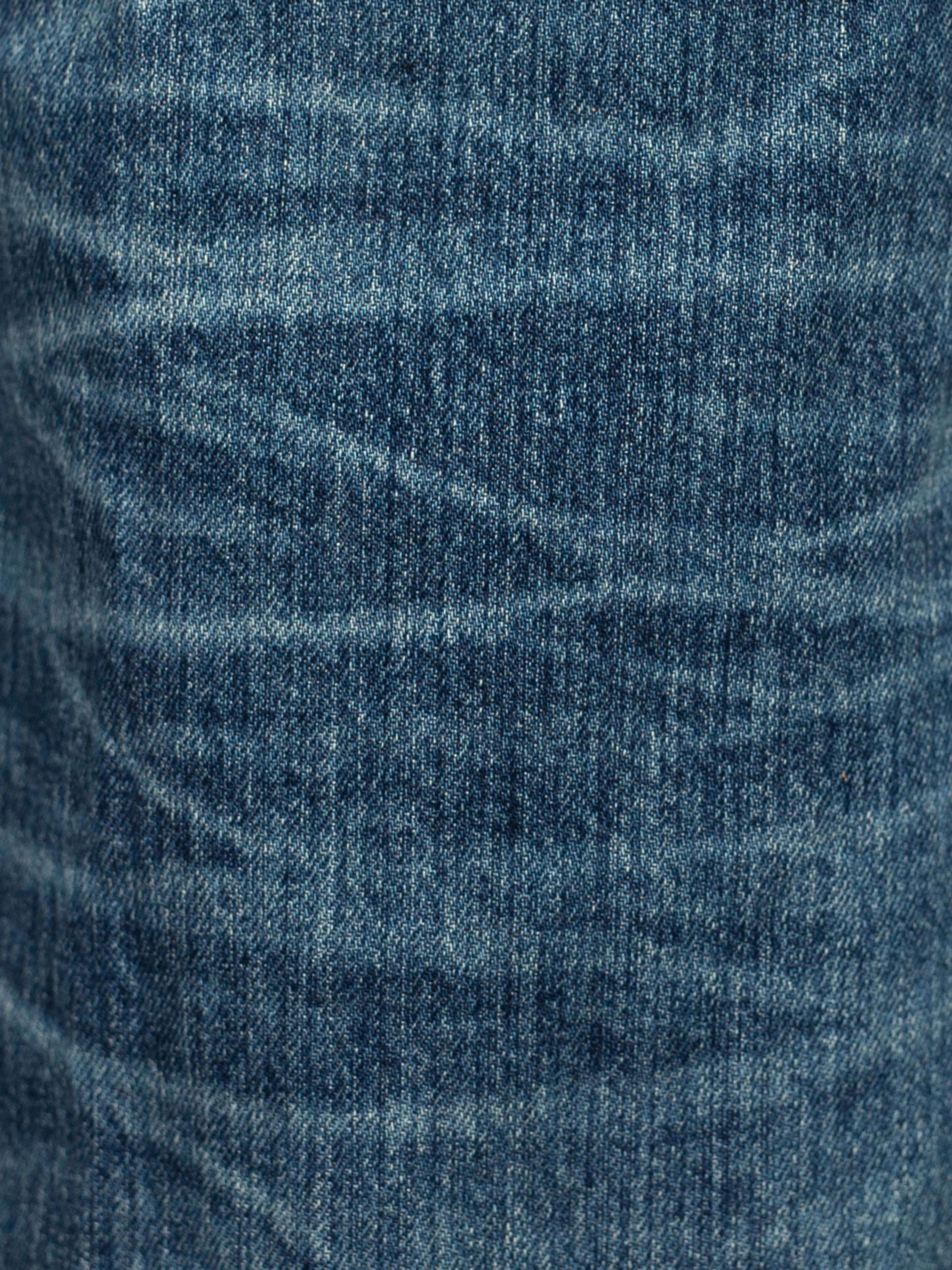 Nudie Jeans Flare Glenn Lineage Tracks mid blue wash, close-up detail of textured organic denim and whisker fading.