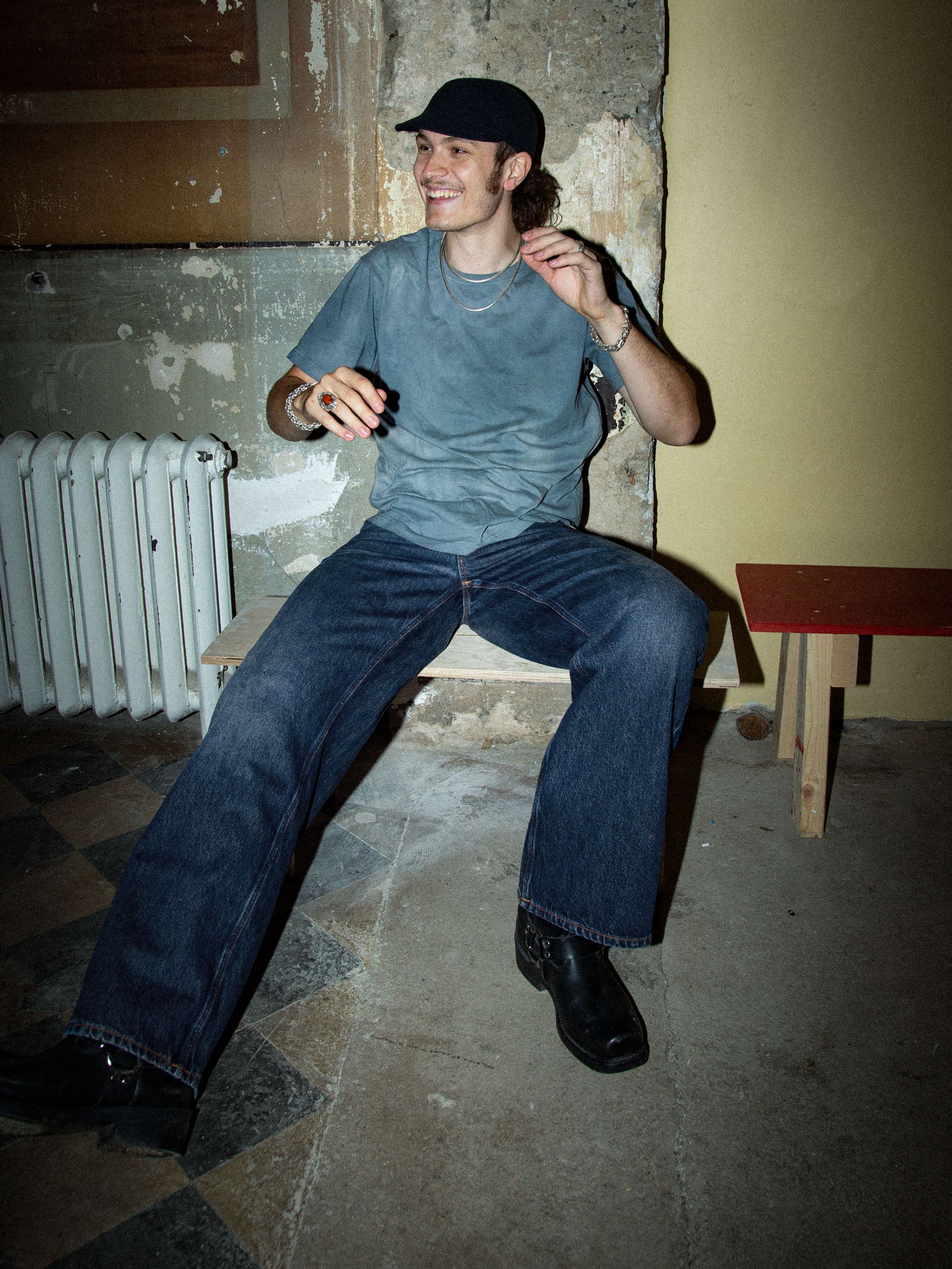 Nudie Jeans Loud Larry Electric Blues, men's loose fit jeans shown on a model sitting on a bench in a full outfit.