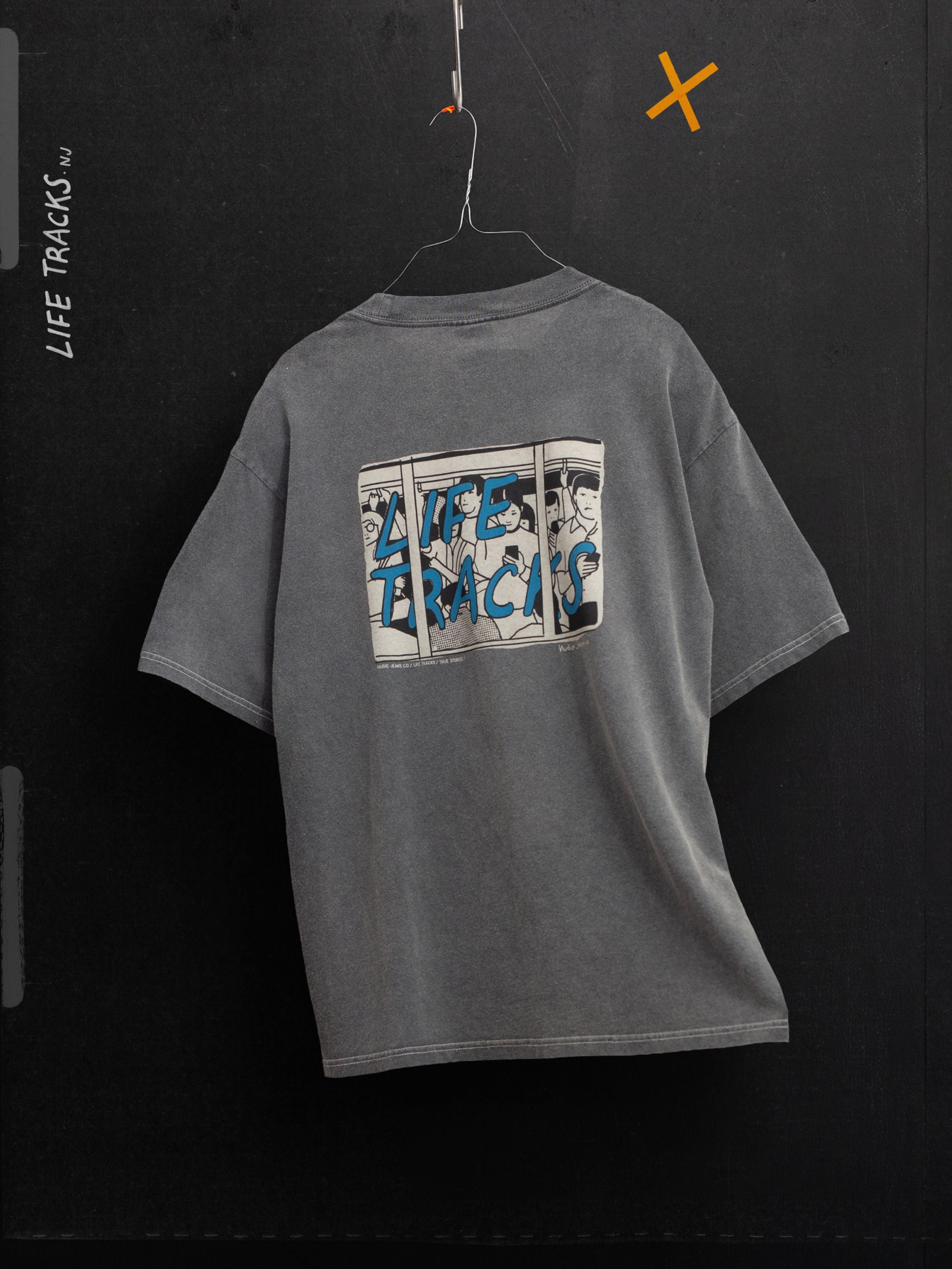Nudie Jeans Koffe T-Shirt LifeTracks III Antracite, an organic cotton tee with a blue back graphic hanging on a wire.