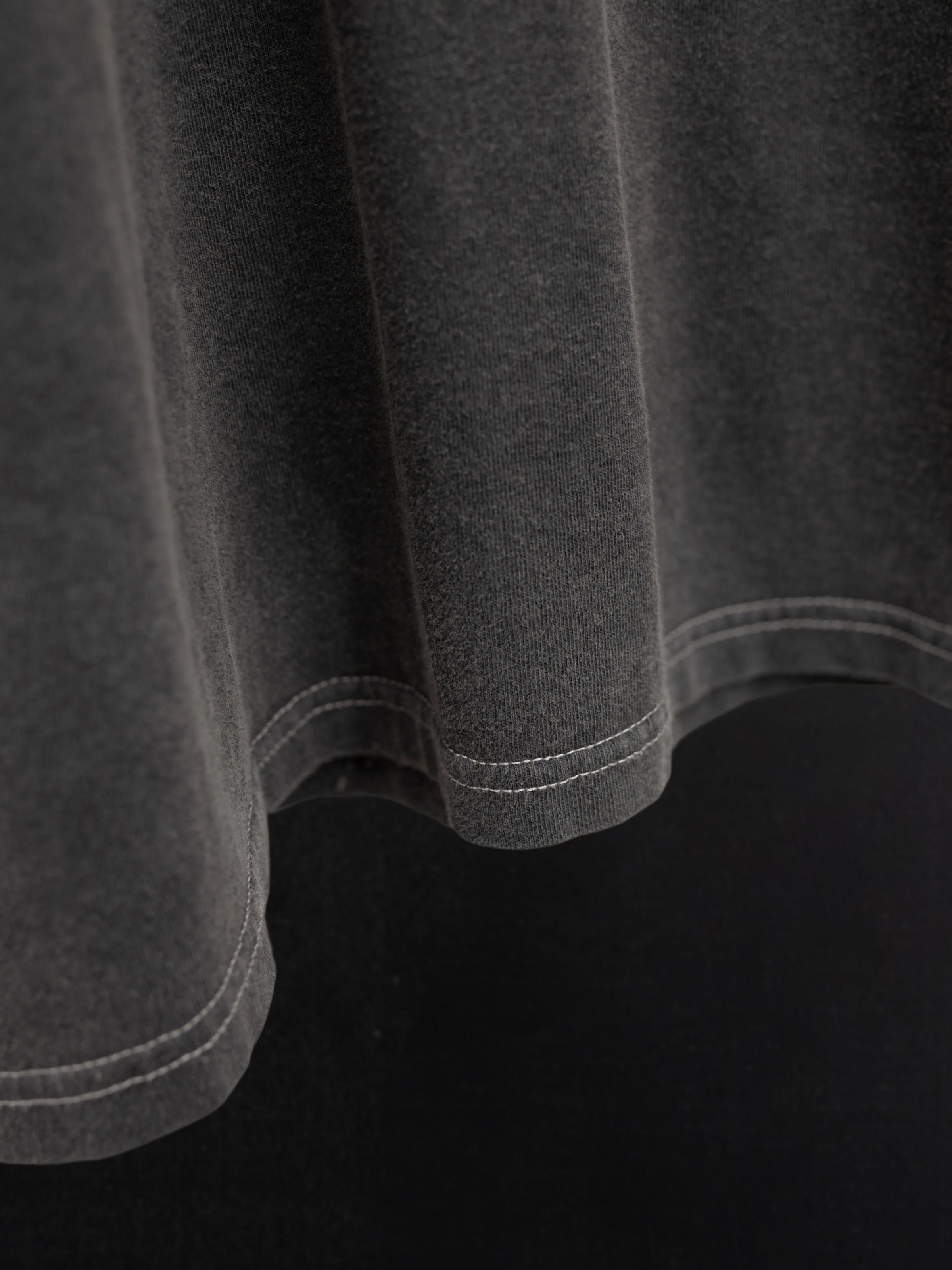 Nudie Jeans Koffe T-Shirt LifeTracks III Antracite, close-up of the hem on vintage-washed organic cotton jersey fabric.