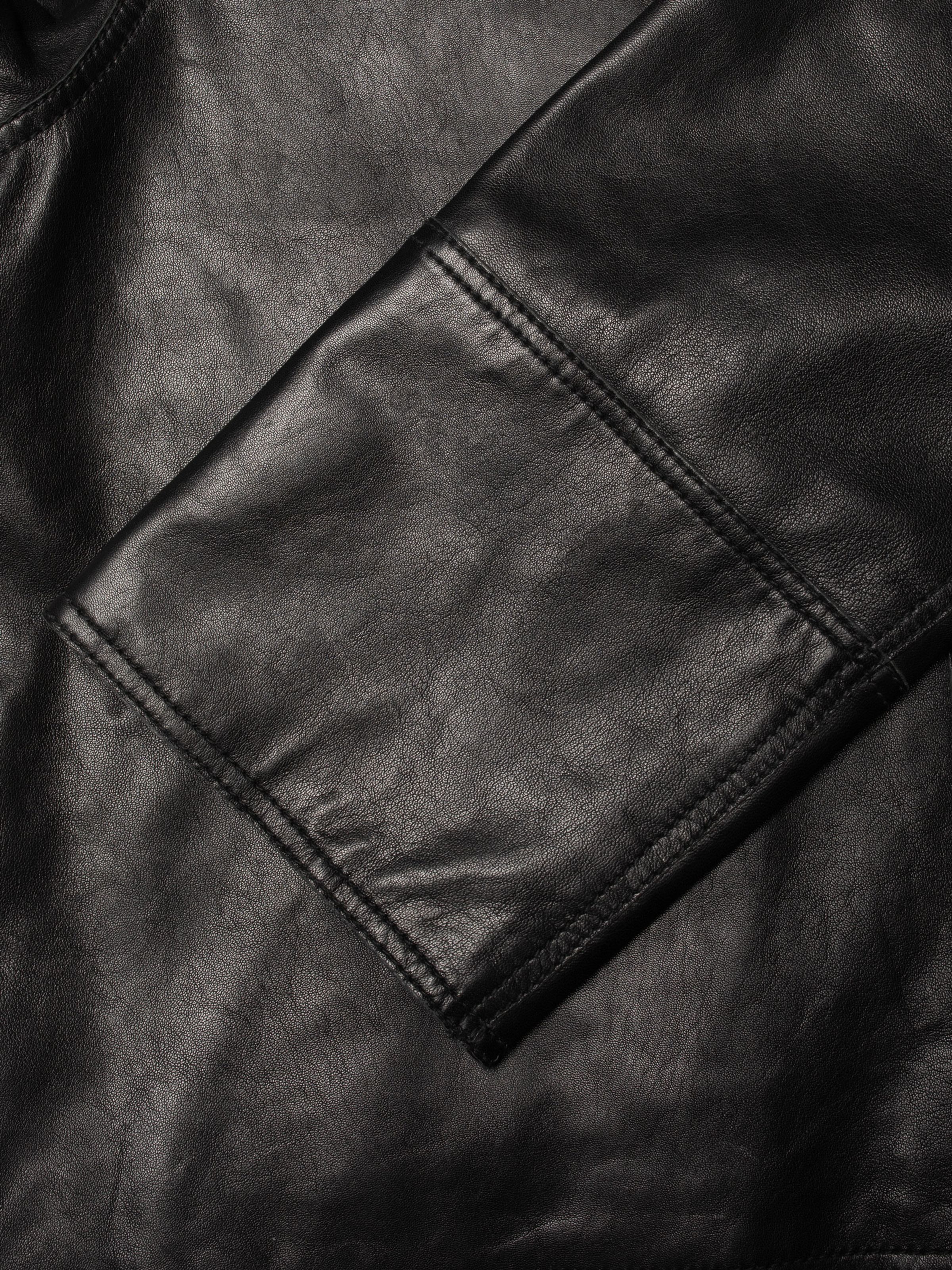 Nudie Jeans Anja Zip Jacket Leather in Black, close-up of the raw-edge hem and three-needle topstitching on lamb skin.
