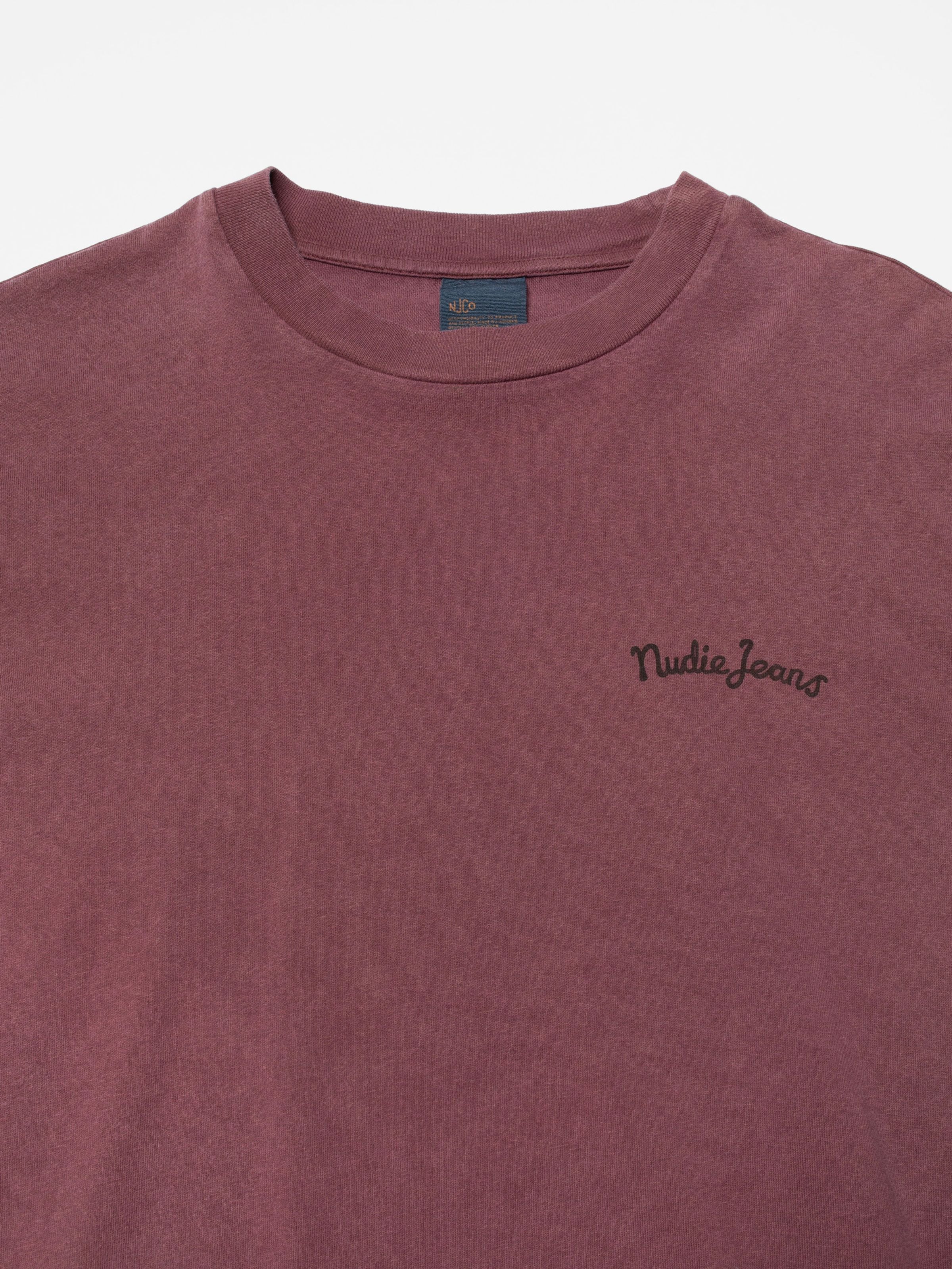 Nudie Jeans Karita T-Shirt in Burgundy organic cotton, close-up view of the chest script logo and ribbed neckline.