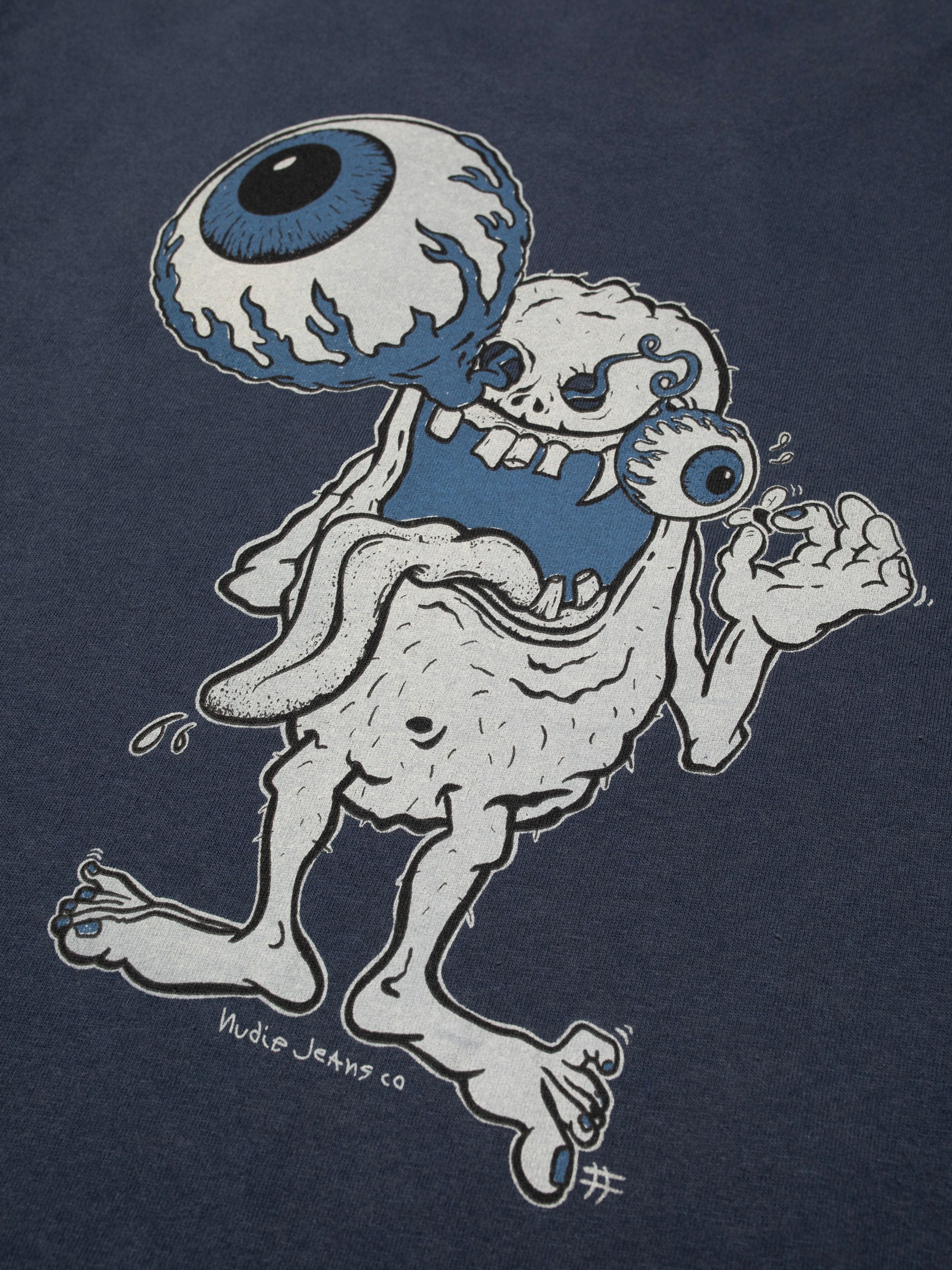 Nudie Jeans Roy T-Shirt Freaky Dark Blue, Nahaufnahme des Monster-Grafikprints auf Jersey aus Bio-Baumwolle.