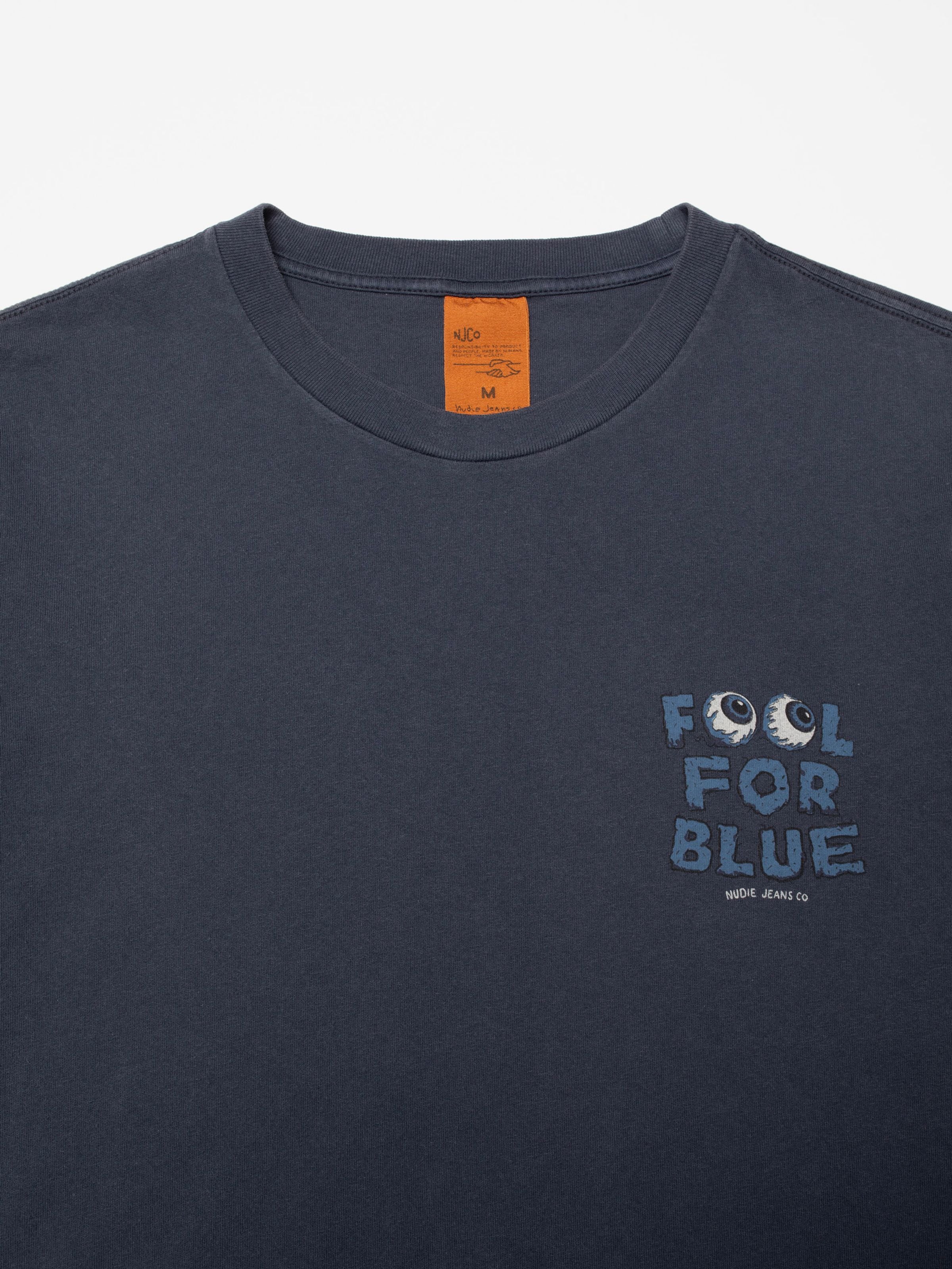 Roy T-Shirt Freaky Dark Blue aus Bio-Baumwolle, Nahaufnahme vom FOOL FOR BLUE Brustprint und orangefarbenem Nackenlabel.