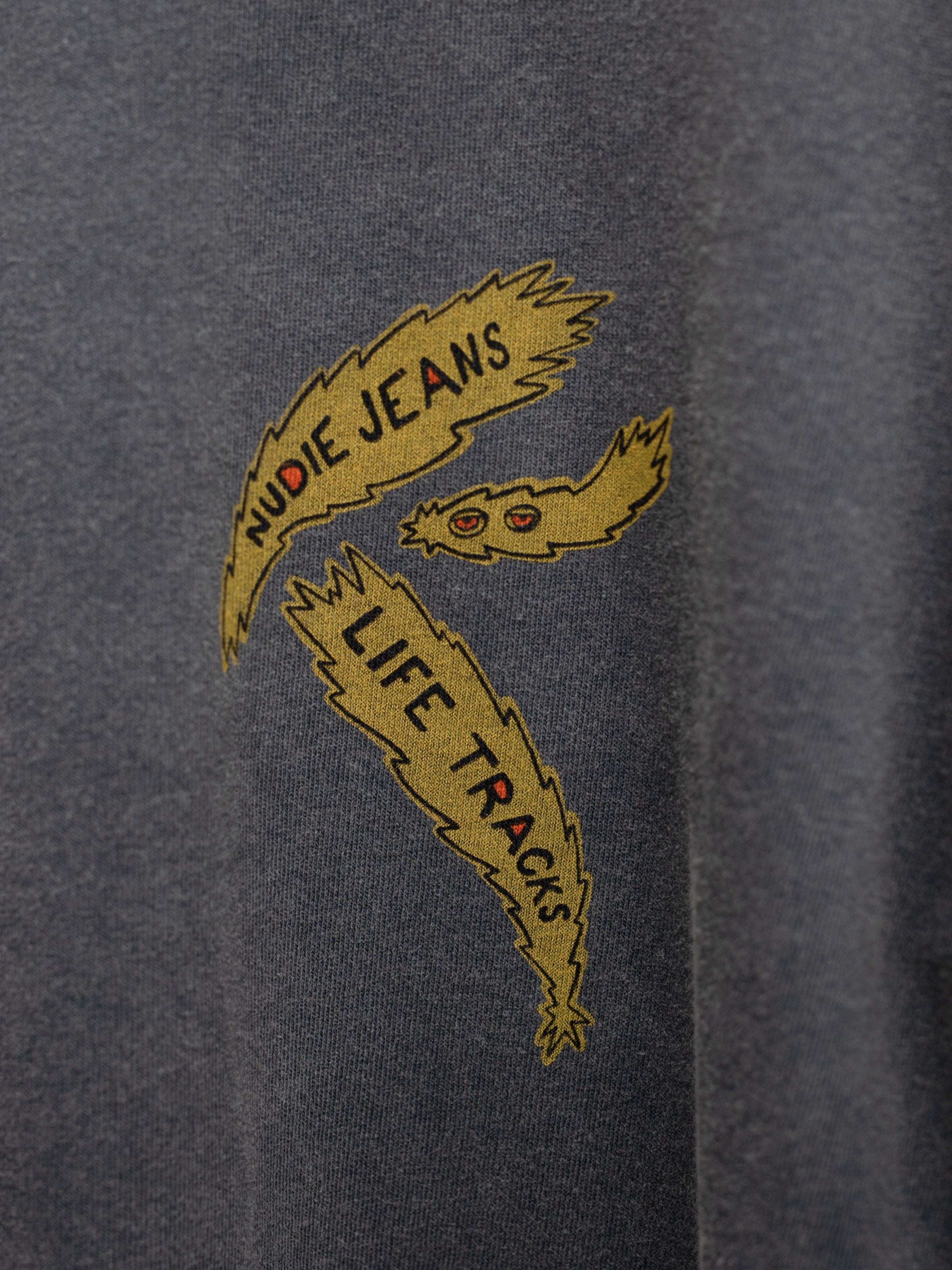 Nudie Jeans Rudi Long Sleeve T-Shirt Life Tracks II in antracite, close-up of the yellow graphic on organic cotton.