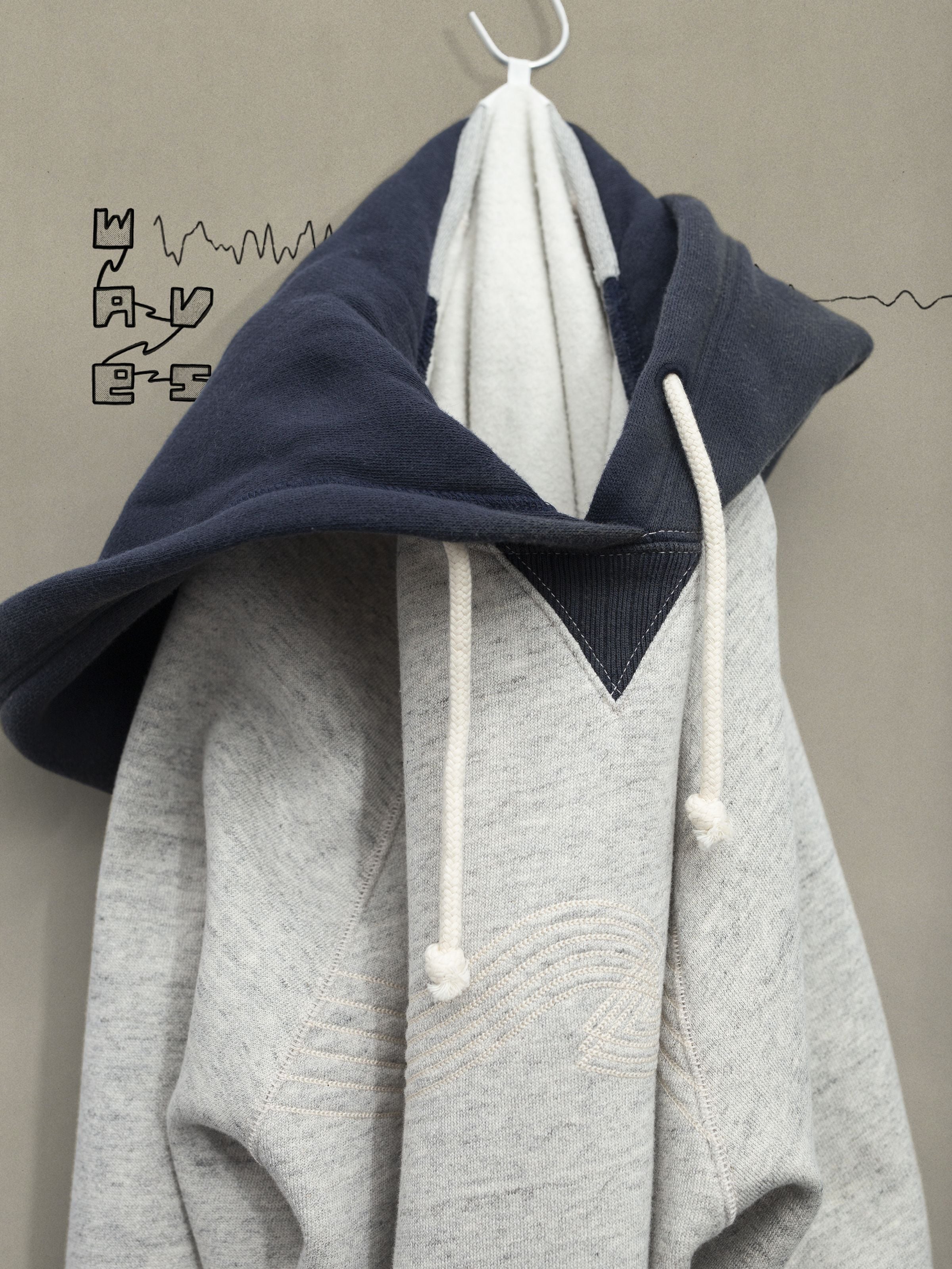 Nudie Jeans Gunde Hoodie Embo Wave in grey melange organic cotton jersey, featuring a navy hood and tonal chest embroidery.