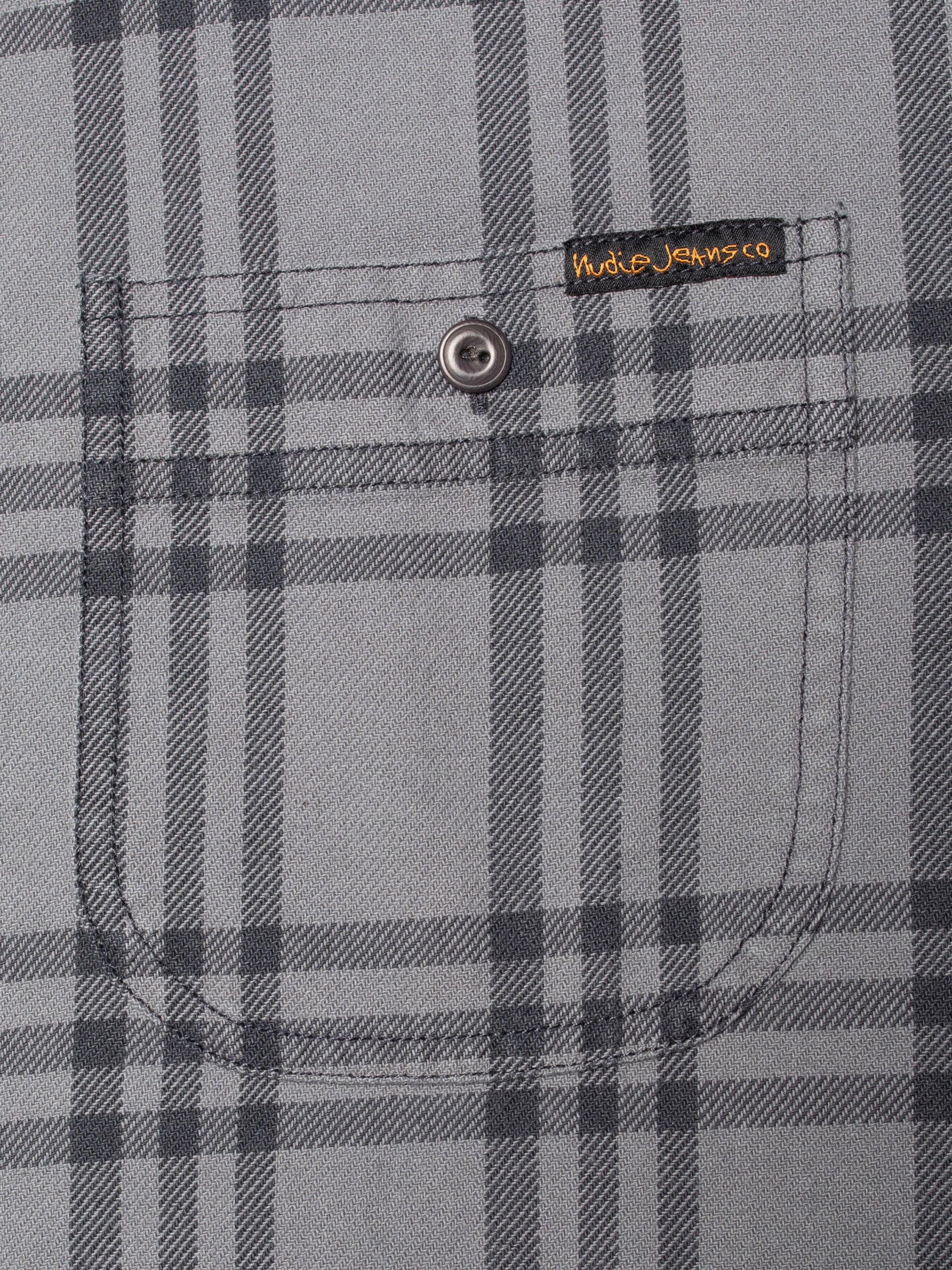 Nudie Jeans Julian Shirt Grey Check in organic cotton, featuring a close-up of the chest pocket and brand label.